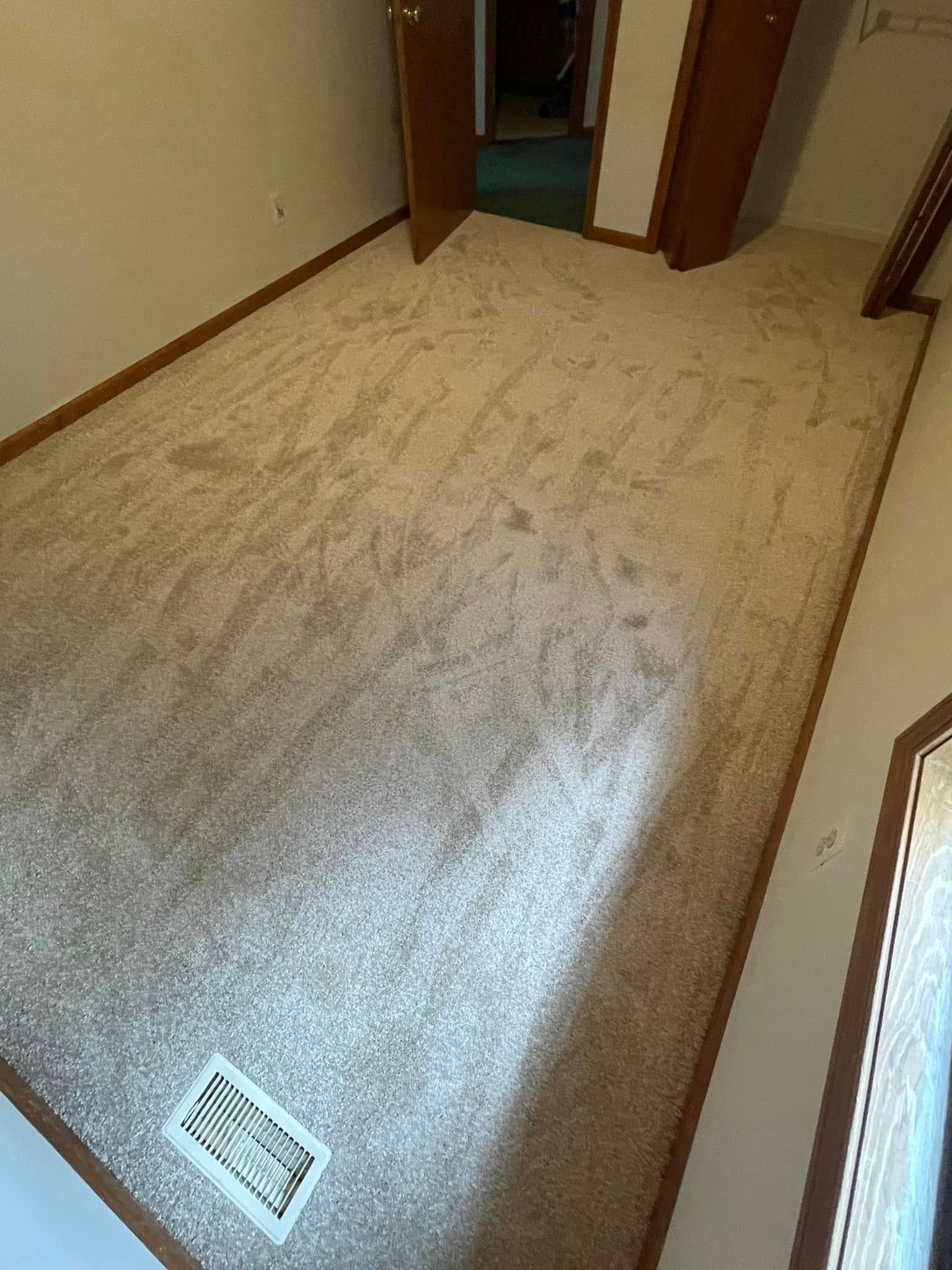 Beige carpeted room with two closed doors, an air vent, and wood trim.