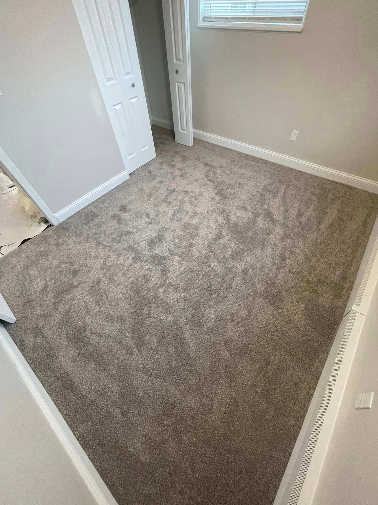 Room with light brown carpet, white trim, and a window.
