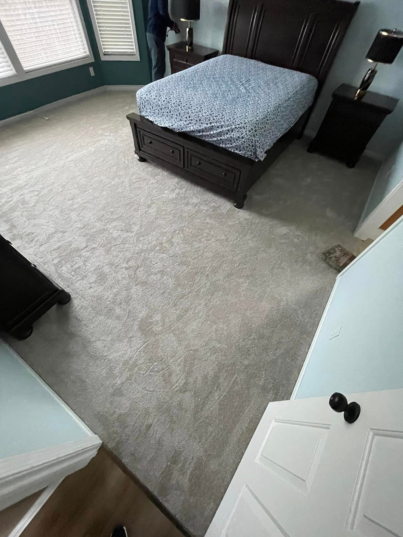Bedroom with dark wooden bed and furniture on light gray carpet.