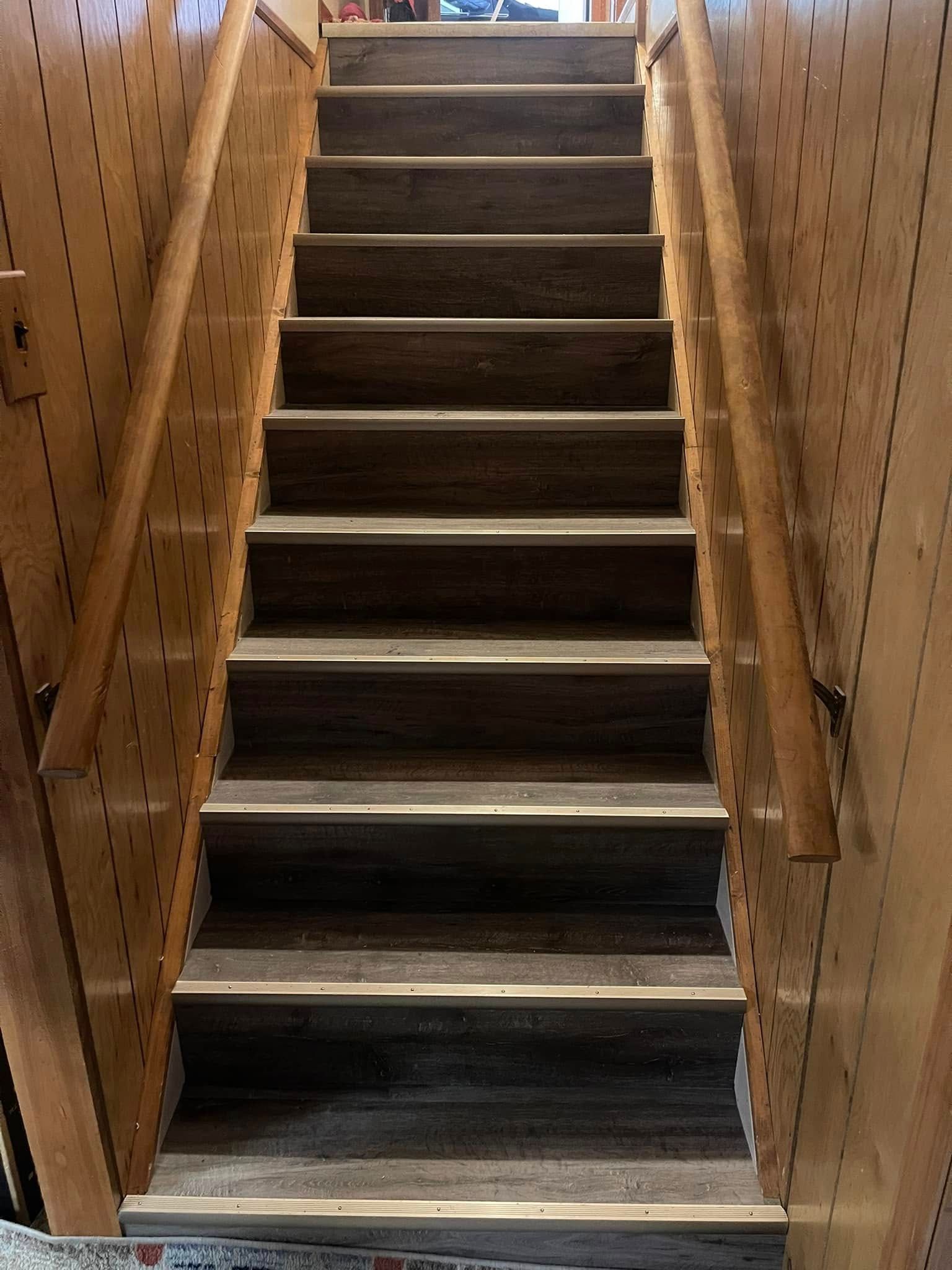 Wooden staircase with pegboard walls and handrails.
