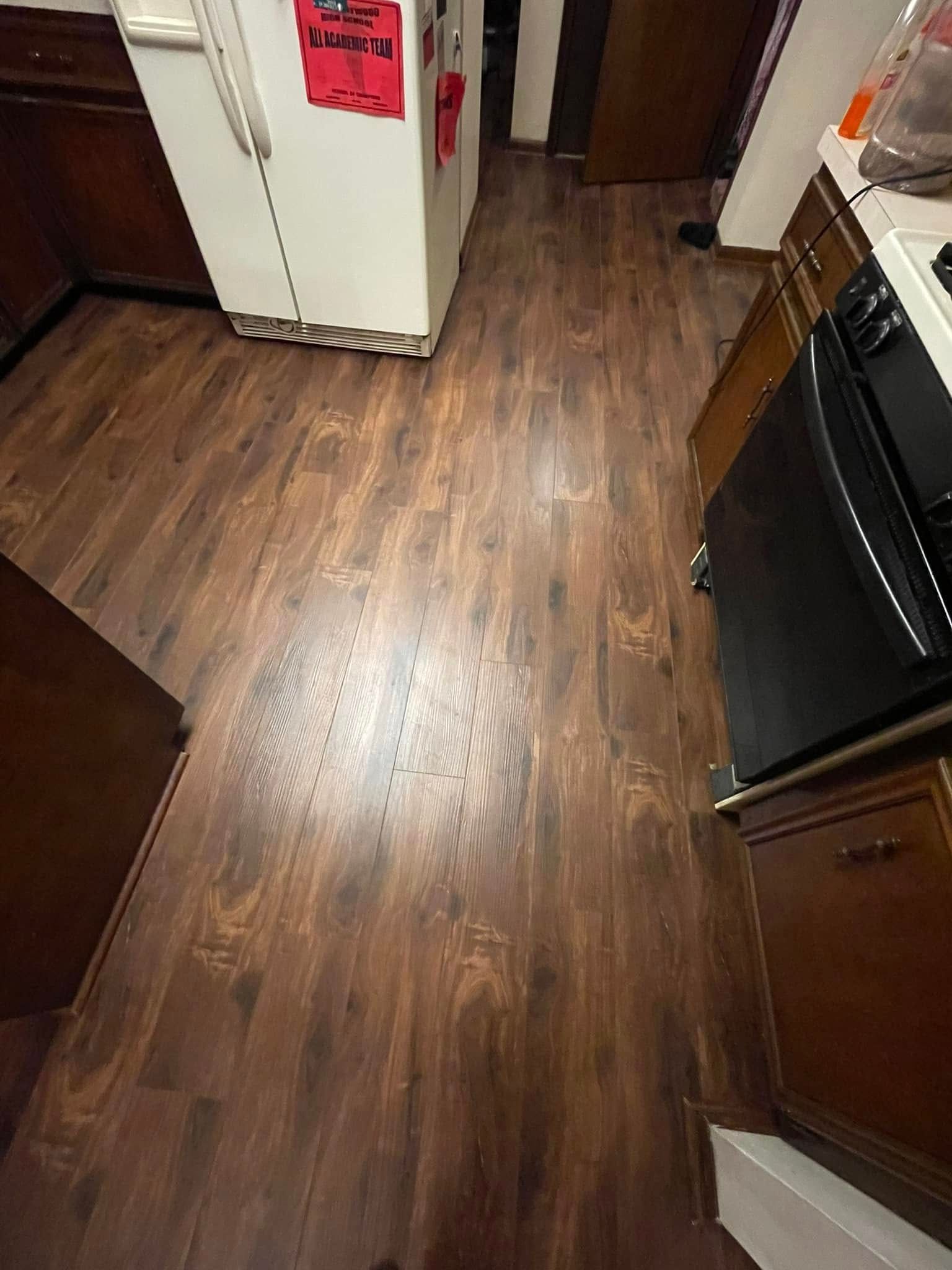 Kitchen with dark brown wood-look flooring, refrigerator, and appliances.