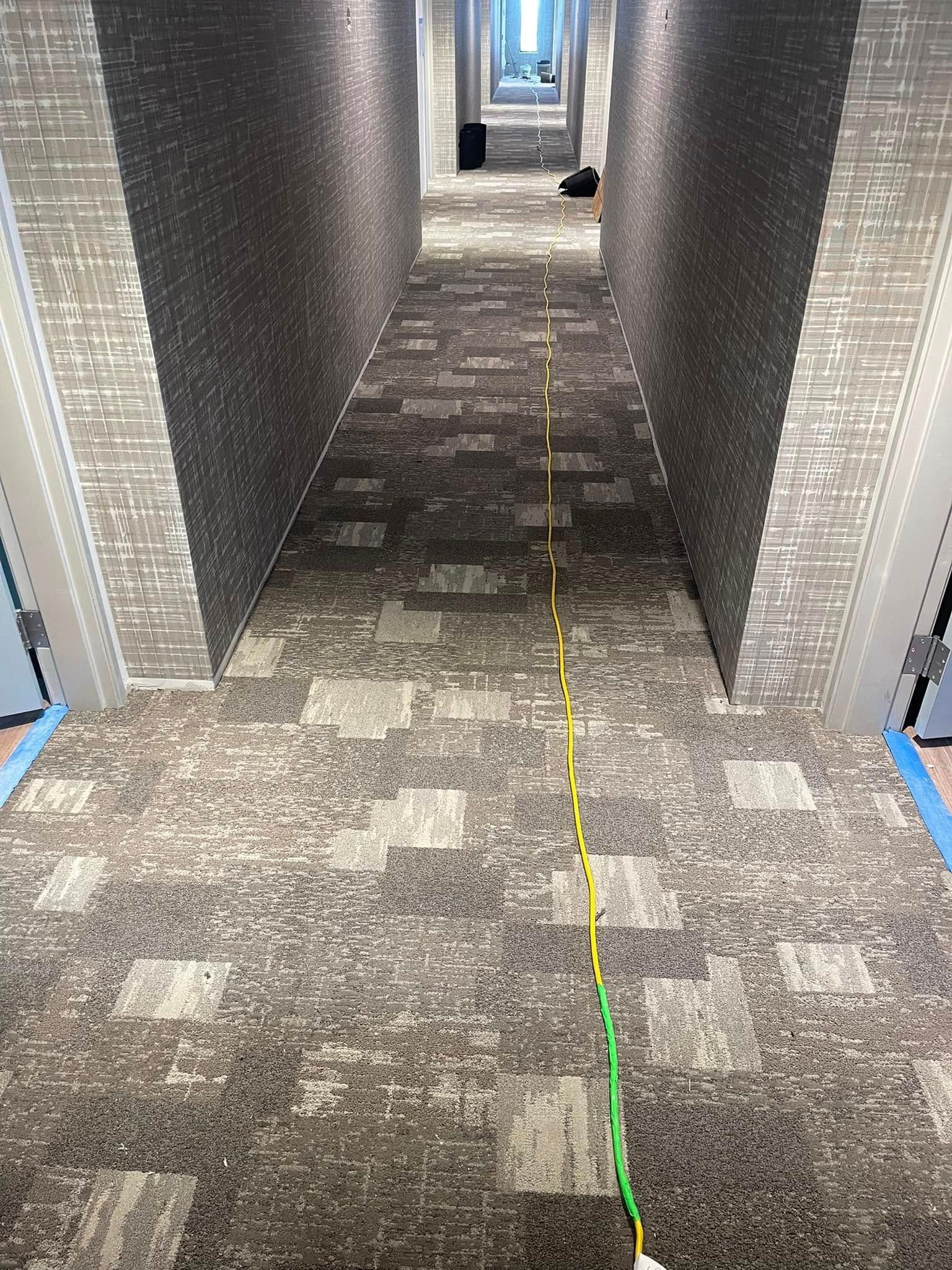 Long hallway with patterned carpet and brick walls; a yellow line runs down the center.