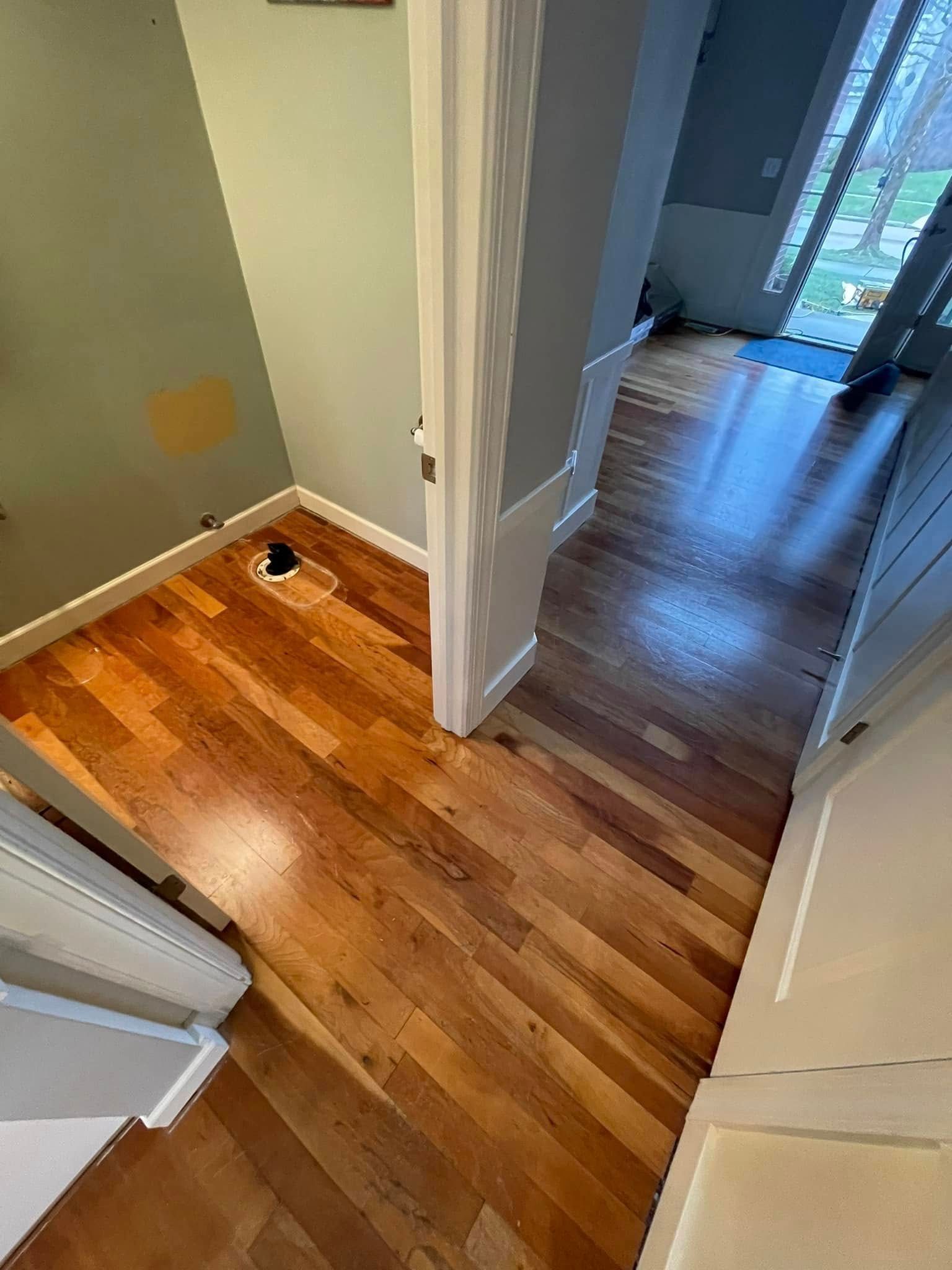 Hardwood floors transition from a room to a doorway, leading to a hallway with stairs.