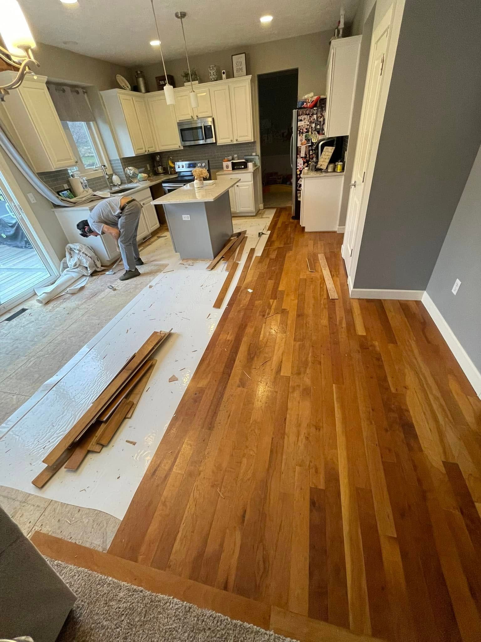 Kitchen with hardwood floor installation in progress, with workers and materials visible.