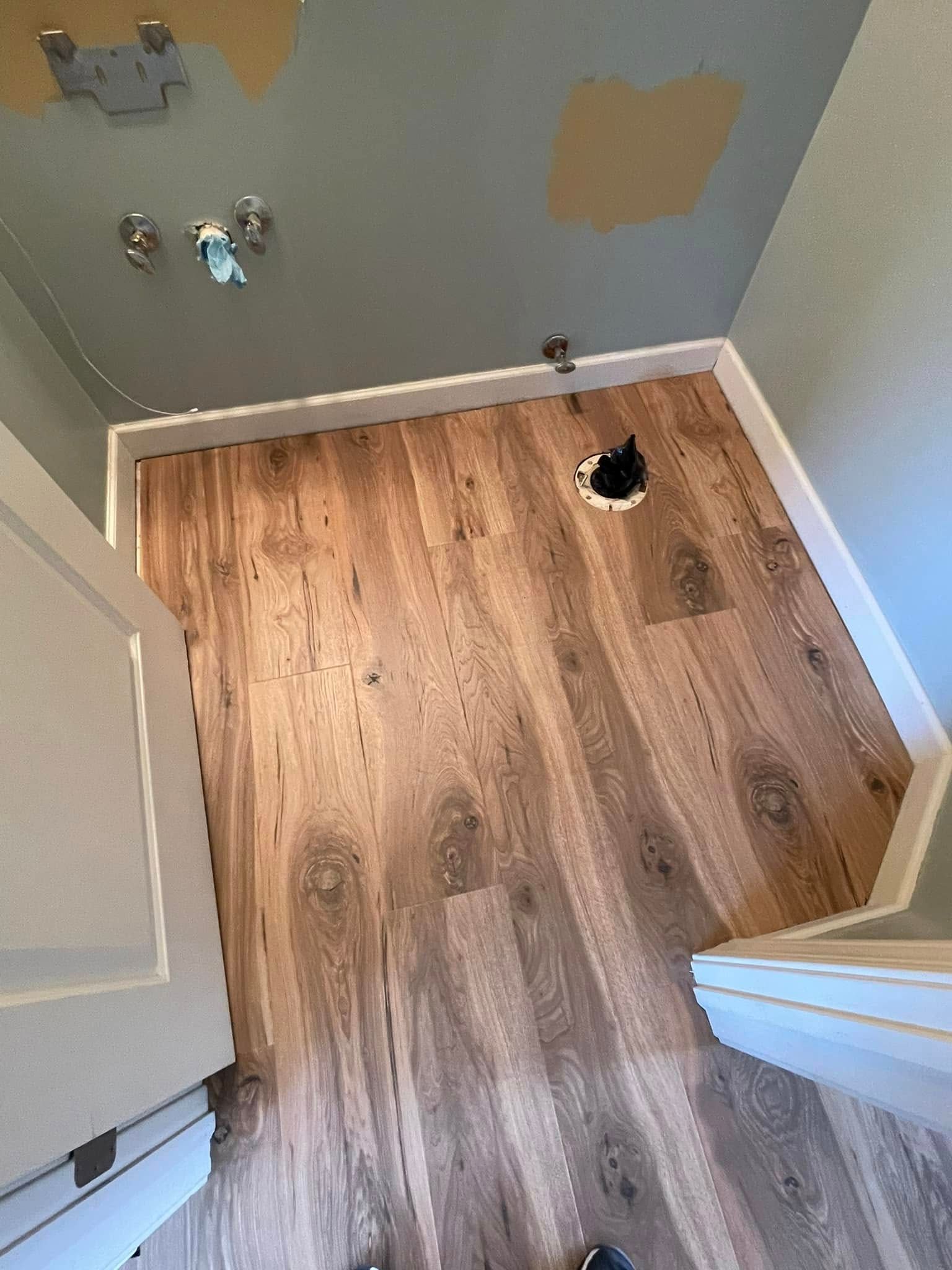 Bathroom with wood-look floor, toilet flange, and white trim. Gray walls.