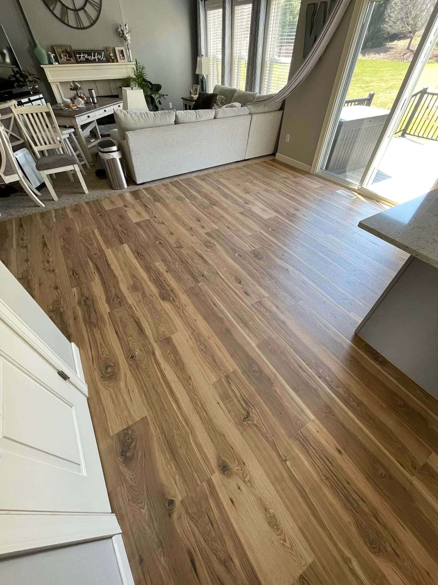 Hardwood flooring in a living space with a sectional sofa, windows, and a counter.