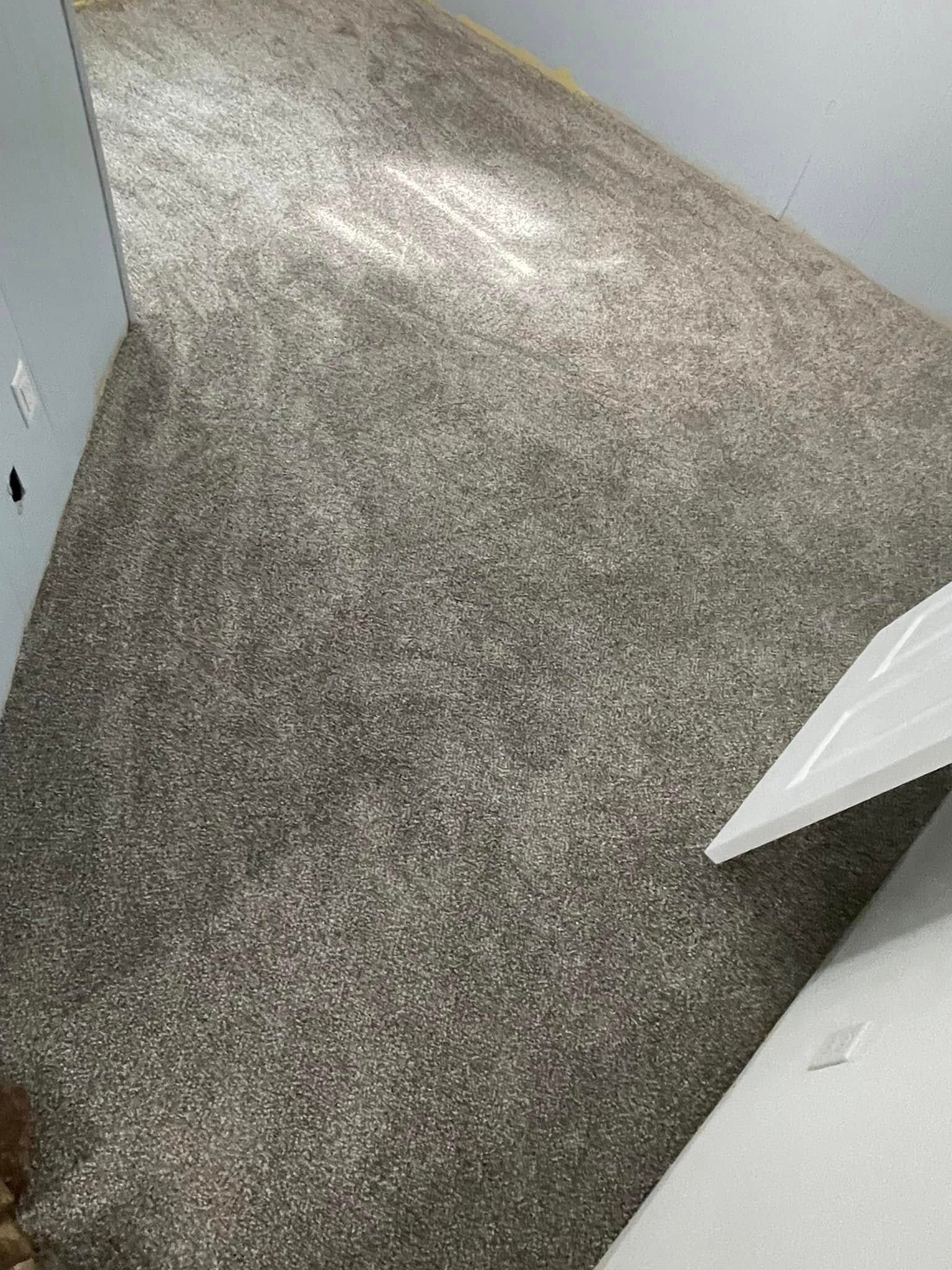 Gray speckled flooring in a room with white trim and a light gray wall.