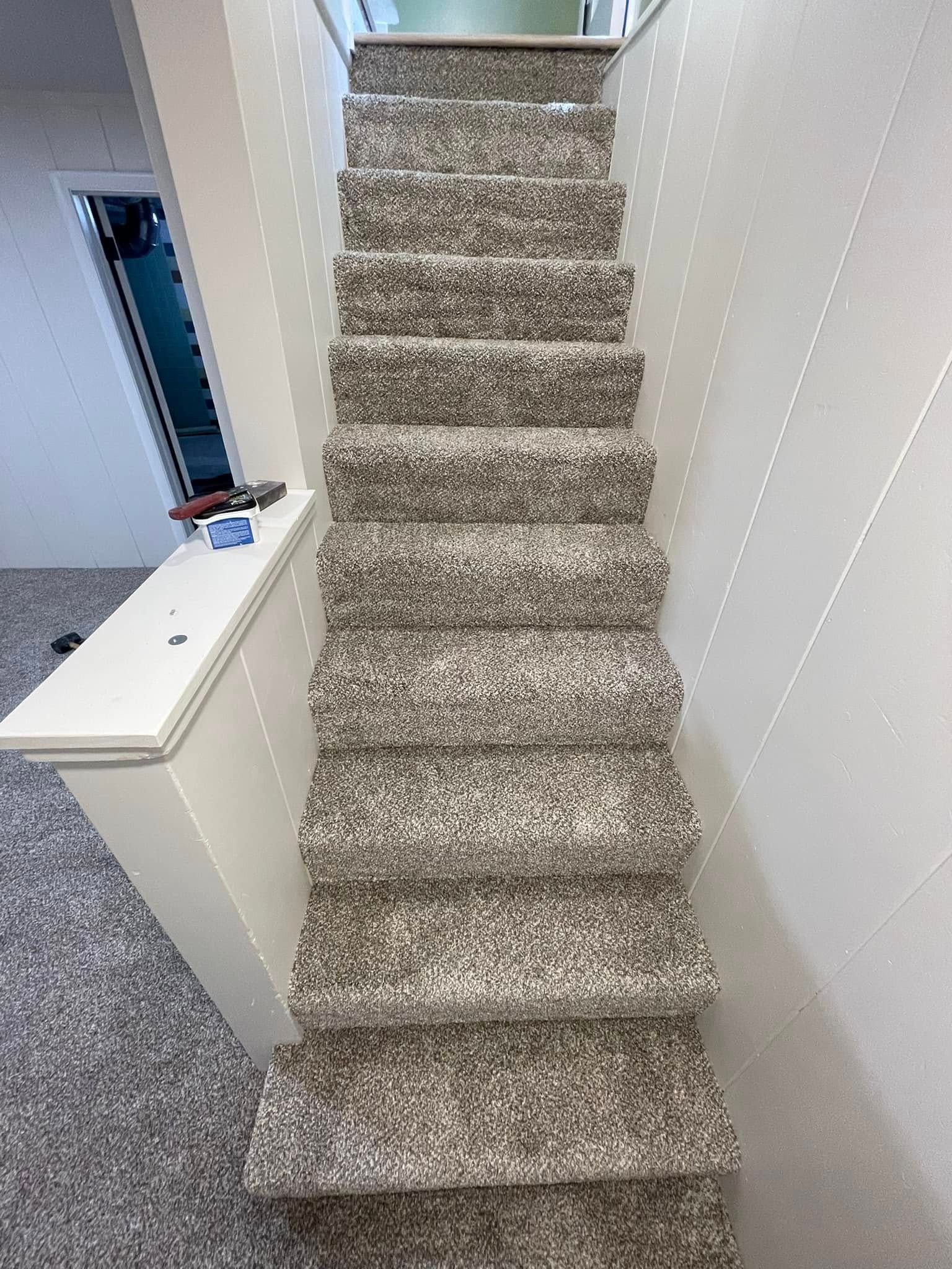Carpeted staircase with white walls.