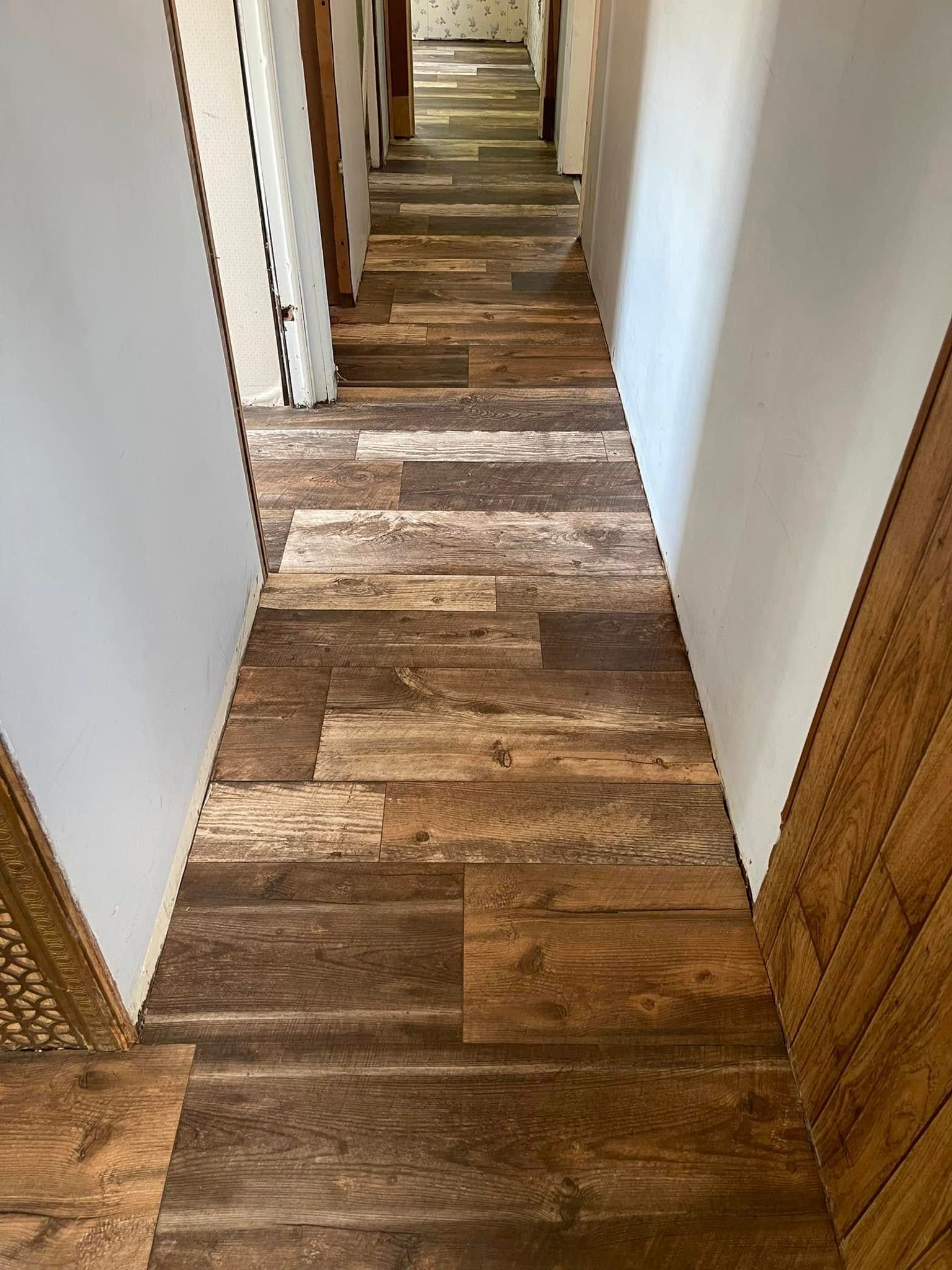 Hallway with wood-look flooring and white walls. Brown and tan planks.