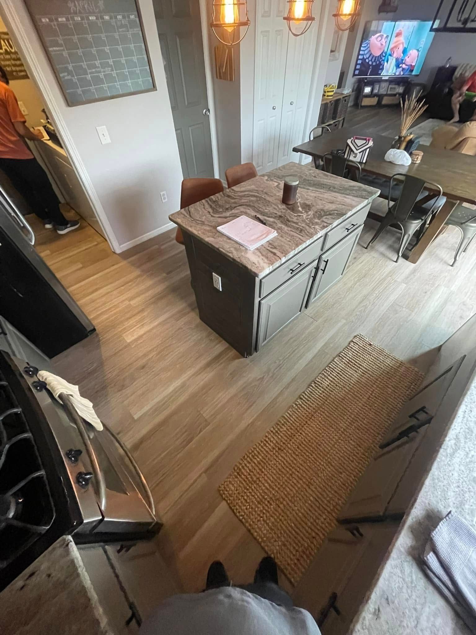 Kitchen with island, hardwood floors, dining table, and rug.