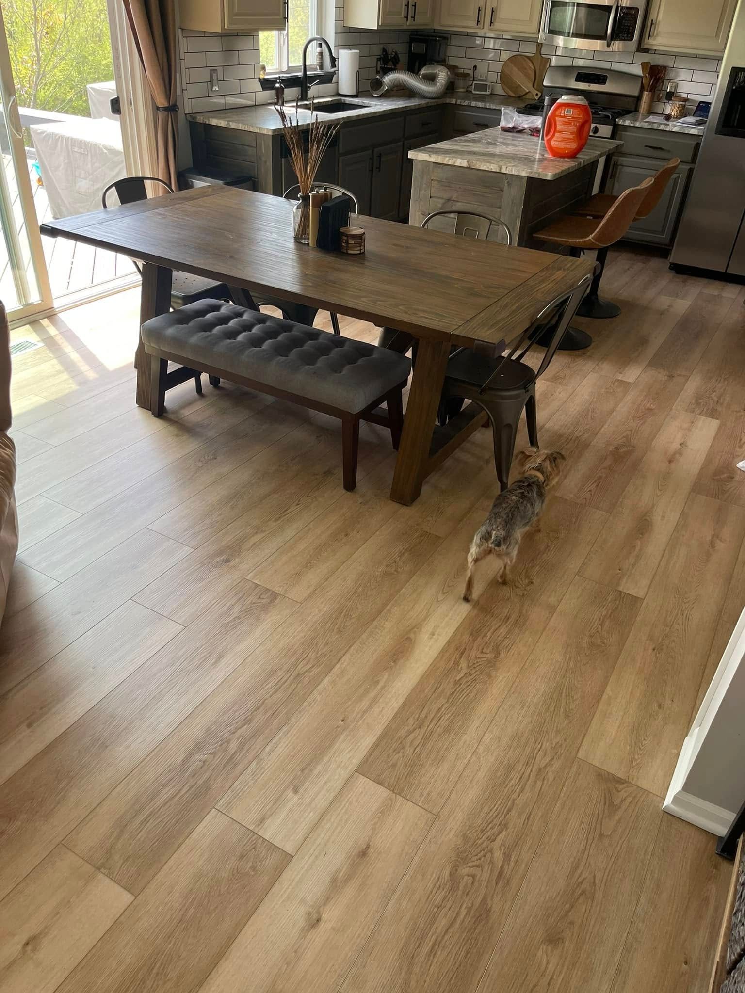 Wooden dining table with bench and dog in a kitchen. Light wood flooring.