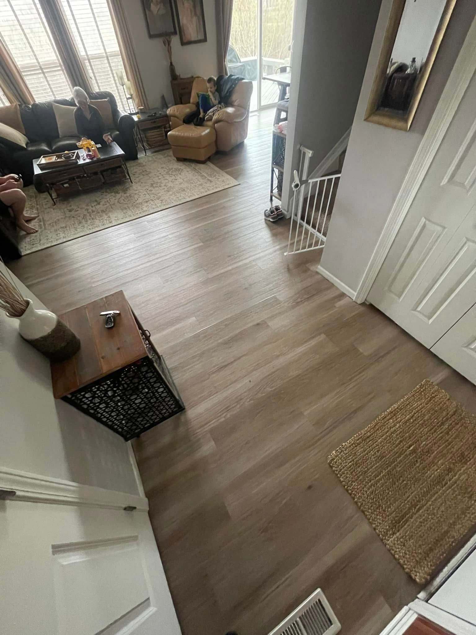 Overhead view of a house interior. Living room with furniture, wood floors, and a small rug near a doorway.