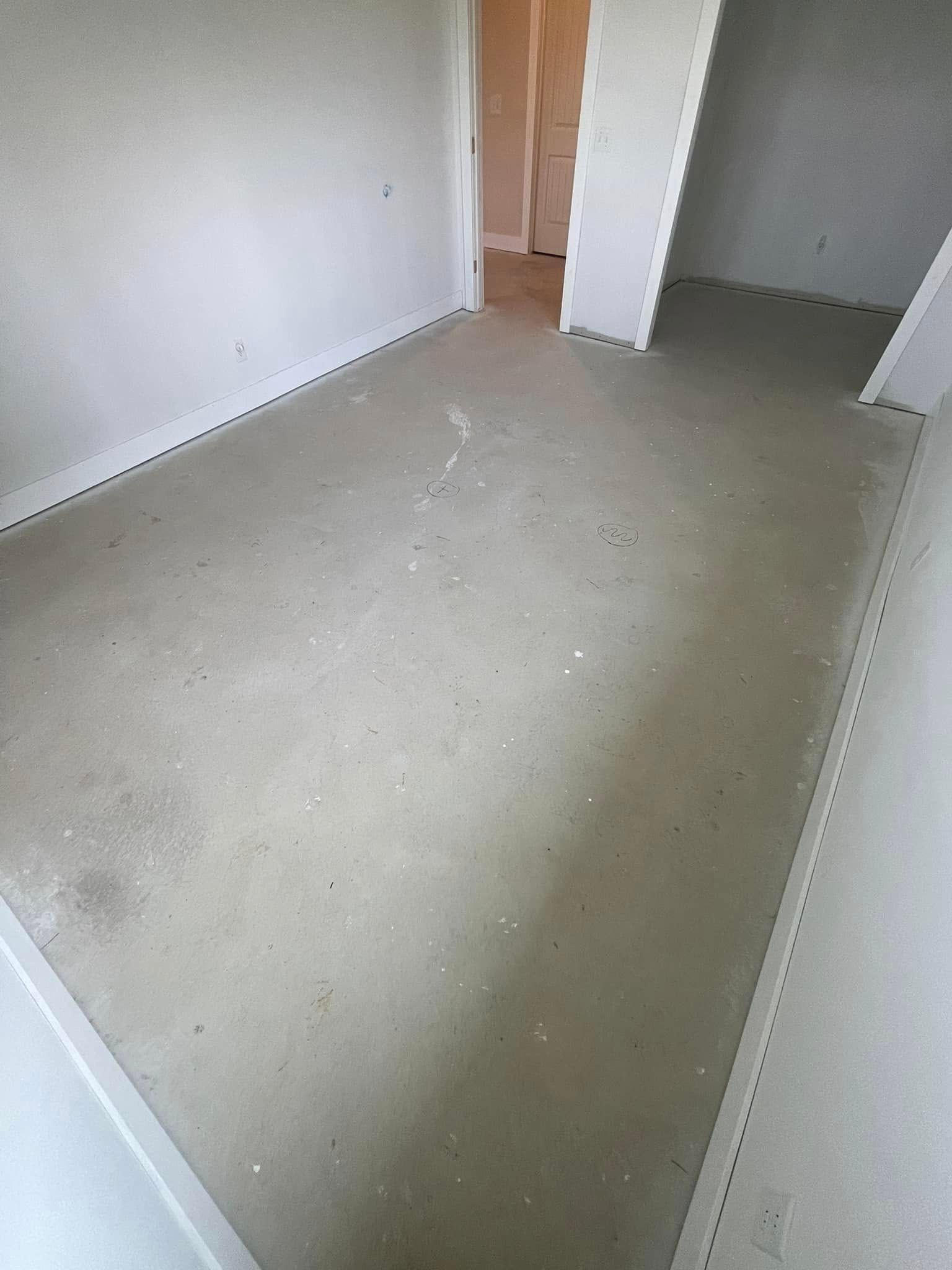 Empty room with light gray concrete floor and white walls. Doorways lead to other rooms.