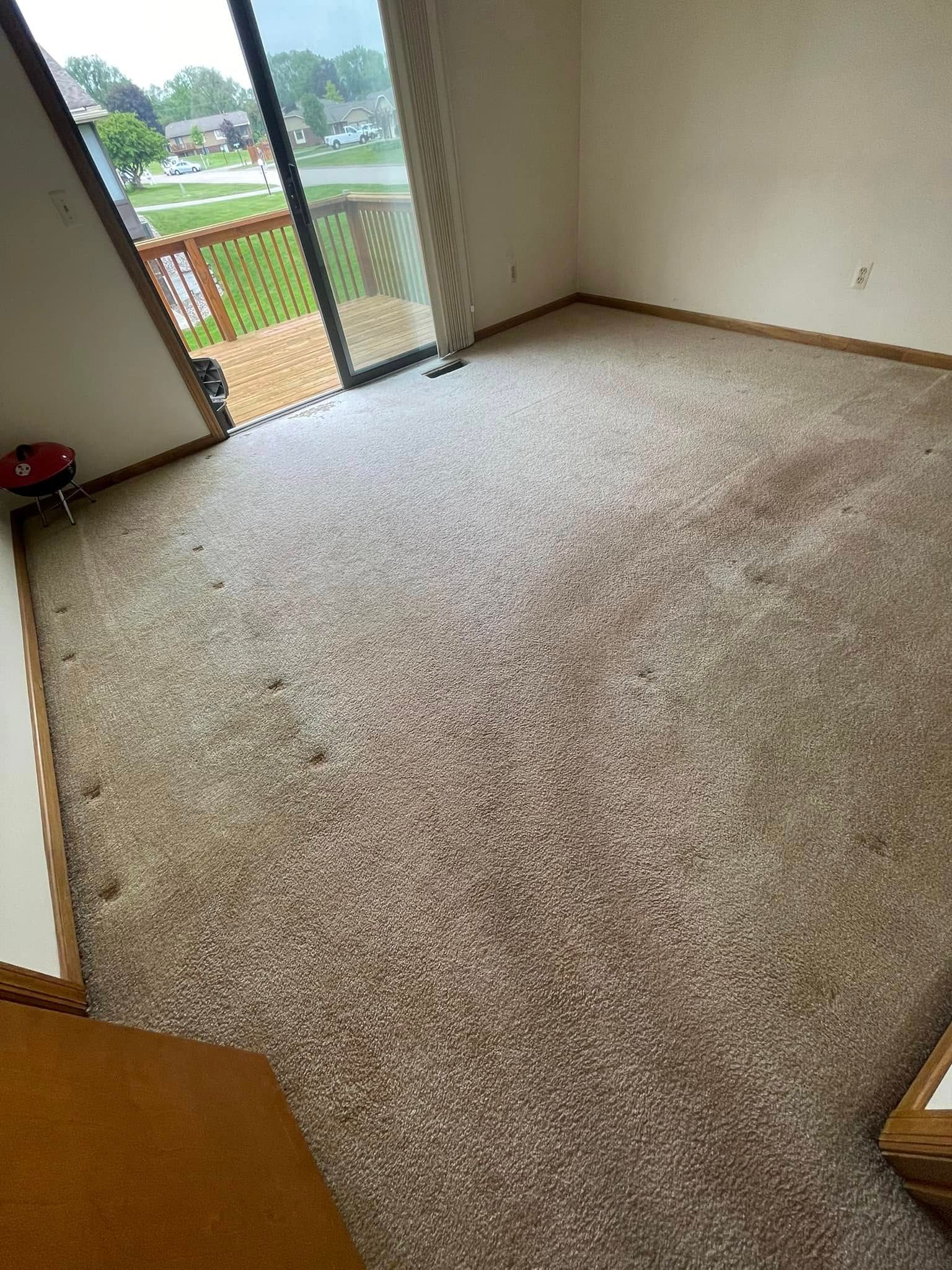 Beige carpeted room with sliding glass door leading to a deck.