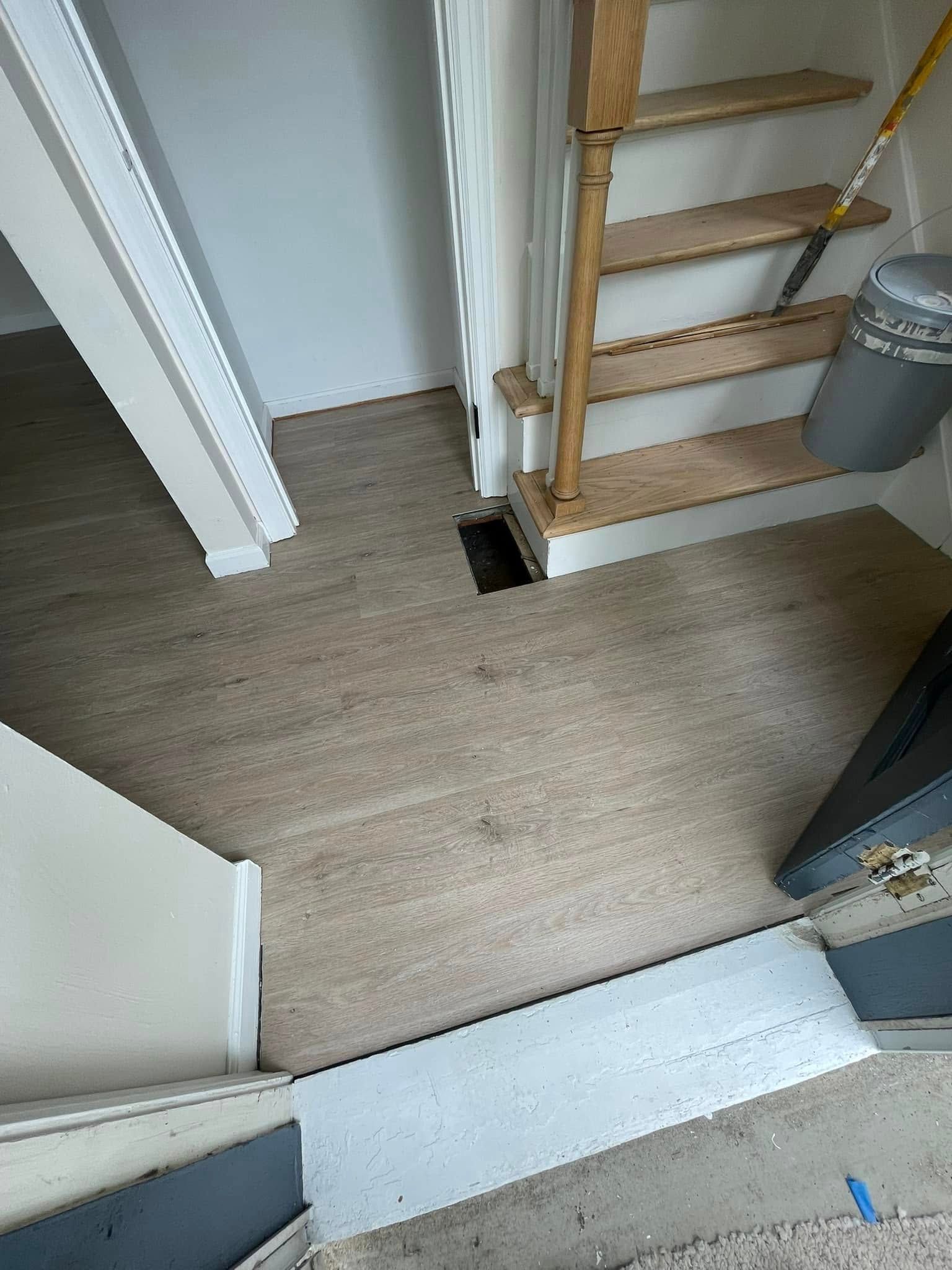 Entryway with carpet, stairs, and a trash can.