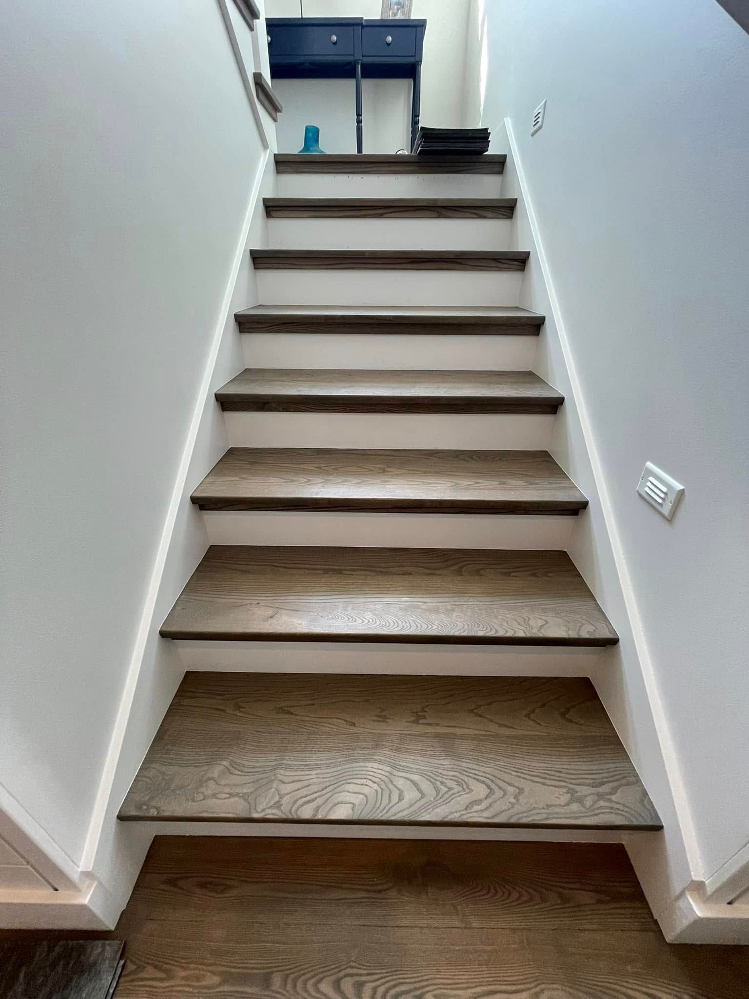 Wooden staircase with white risers and dark wood treads, leading upwards.