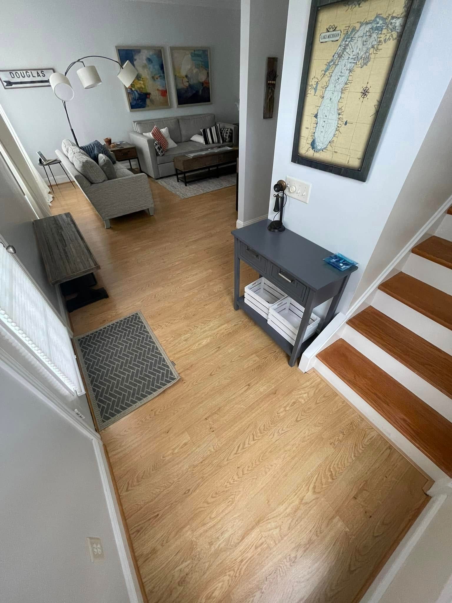 Wooden floor hallway with entryway table, staircase, and living room visible.