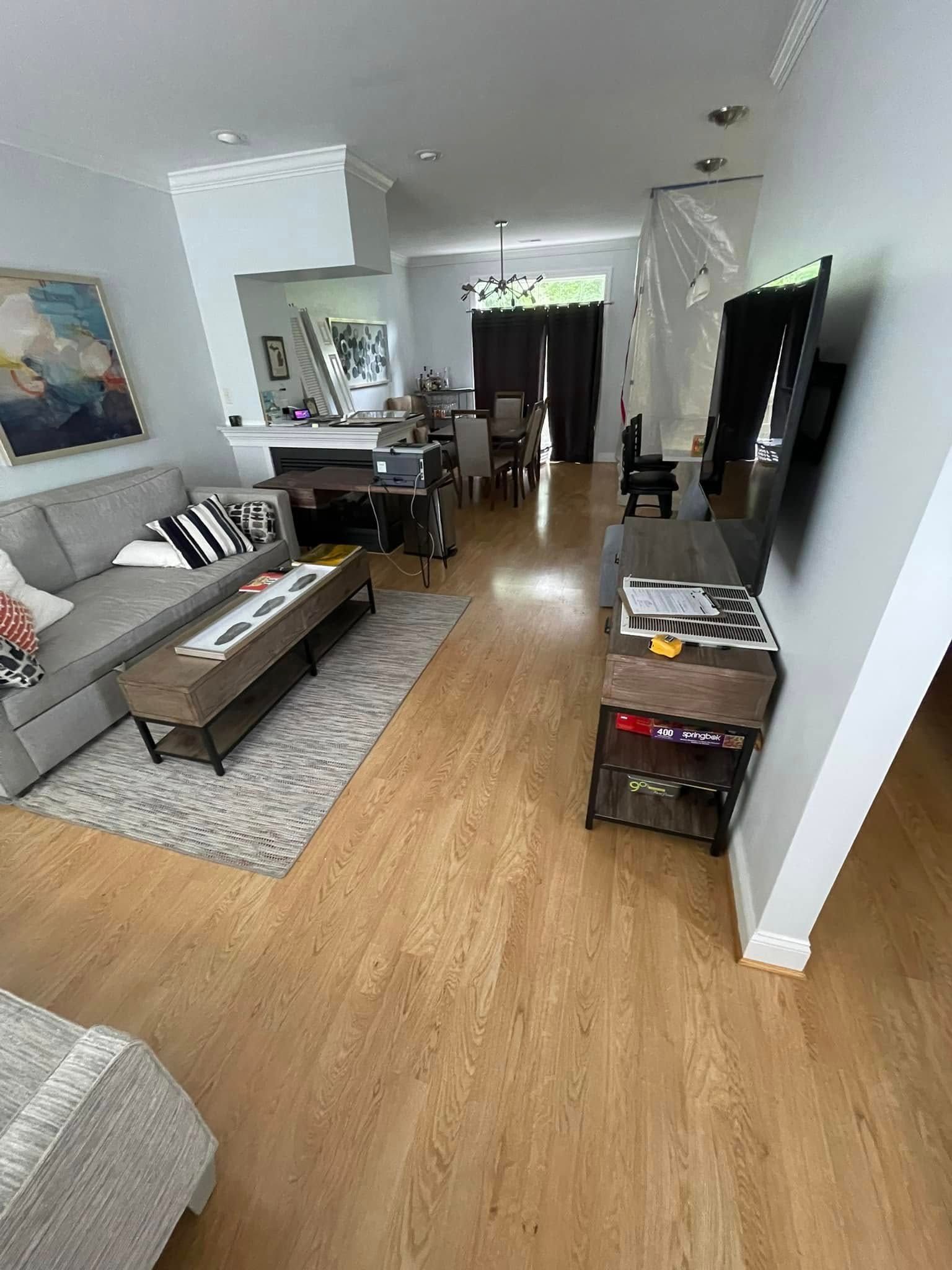 A living room with a couch, coffee table, rug, and TV stand. The floors are light brown.