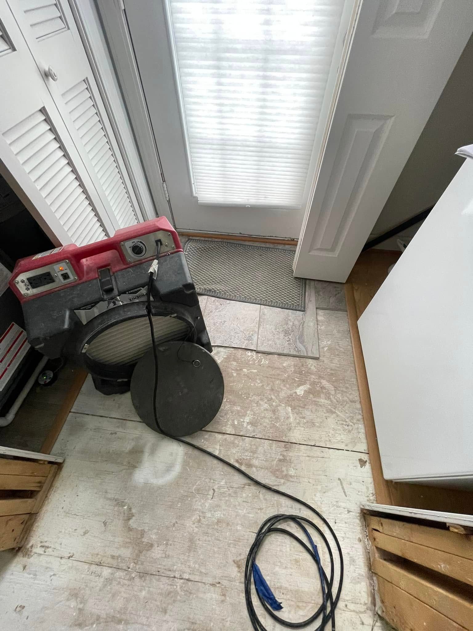 A dehumidifier and heater sit on a floor. A window with blinds is overhead.