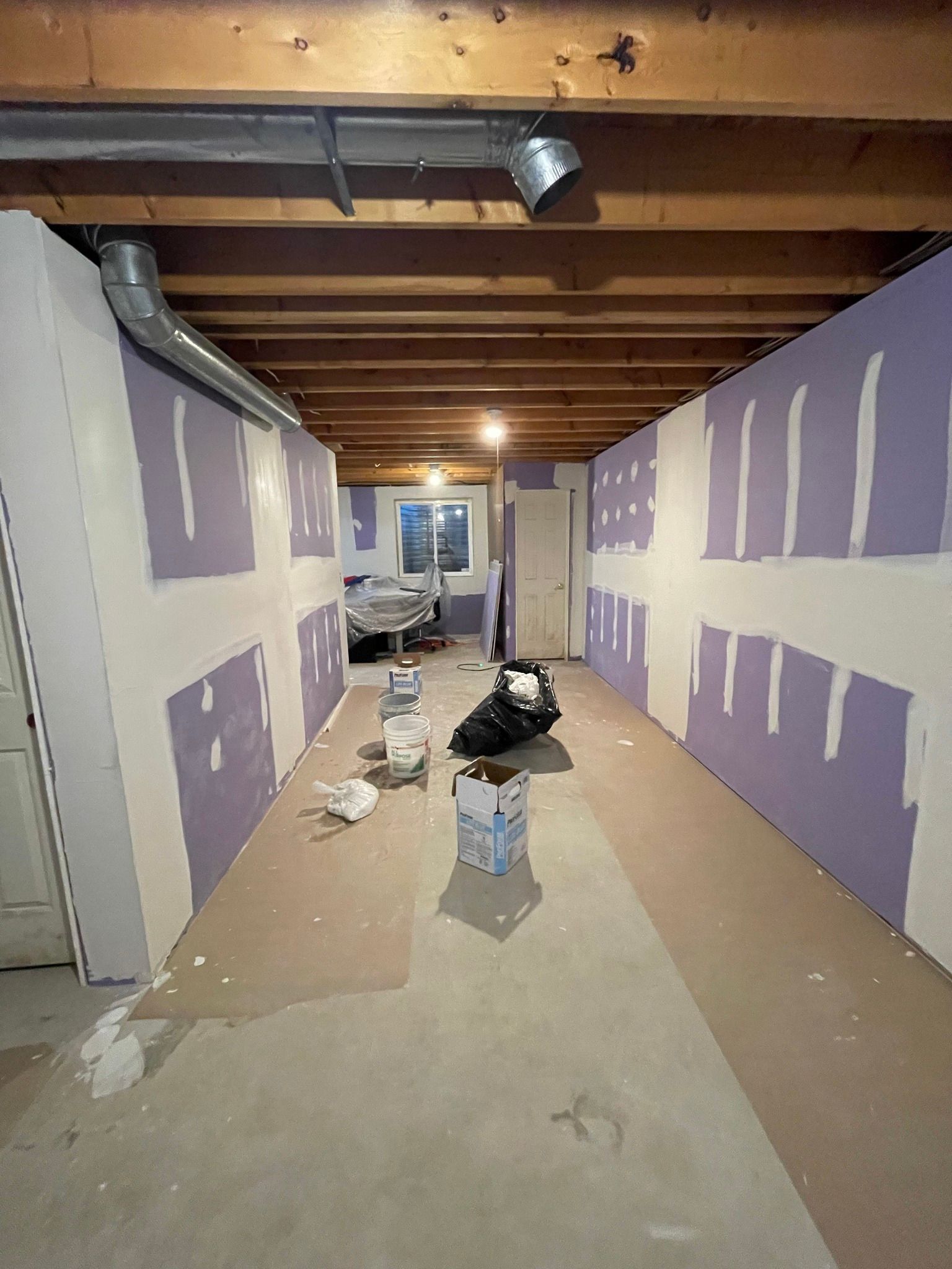 Basement renovation in progress, drywall installed on walls. Tools and supplies scattered on the floor.