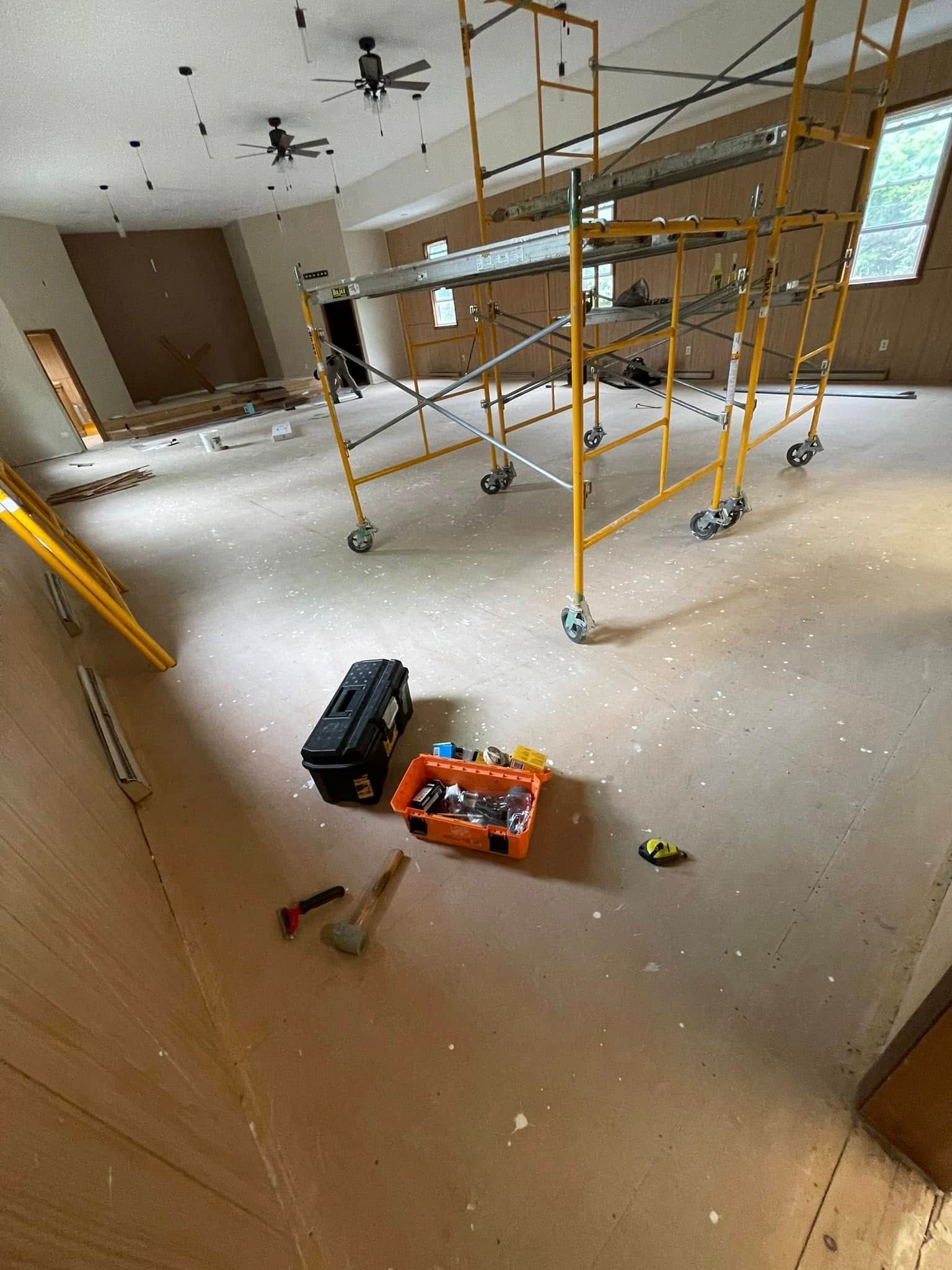 Room renovation with scaffolding, tools, and debris on the floor.