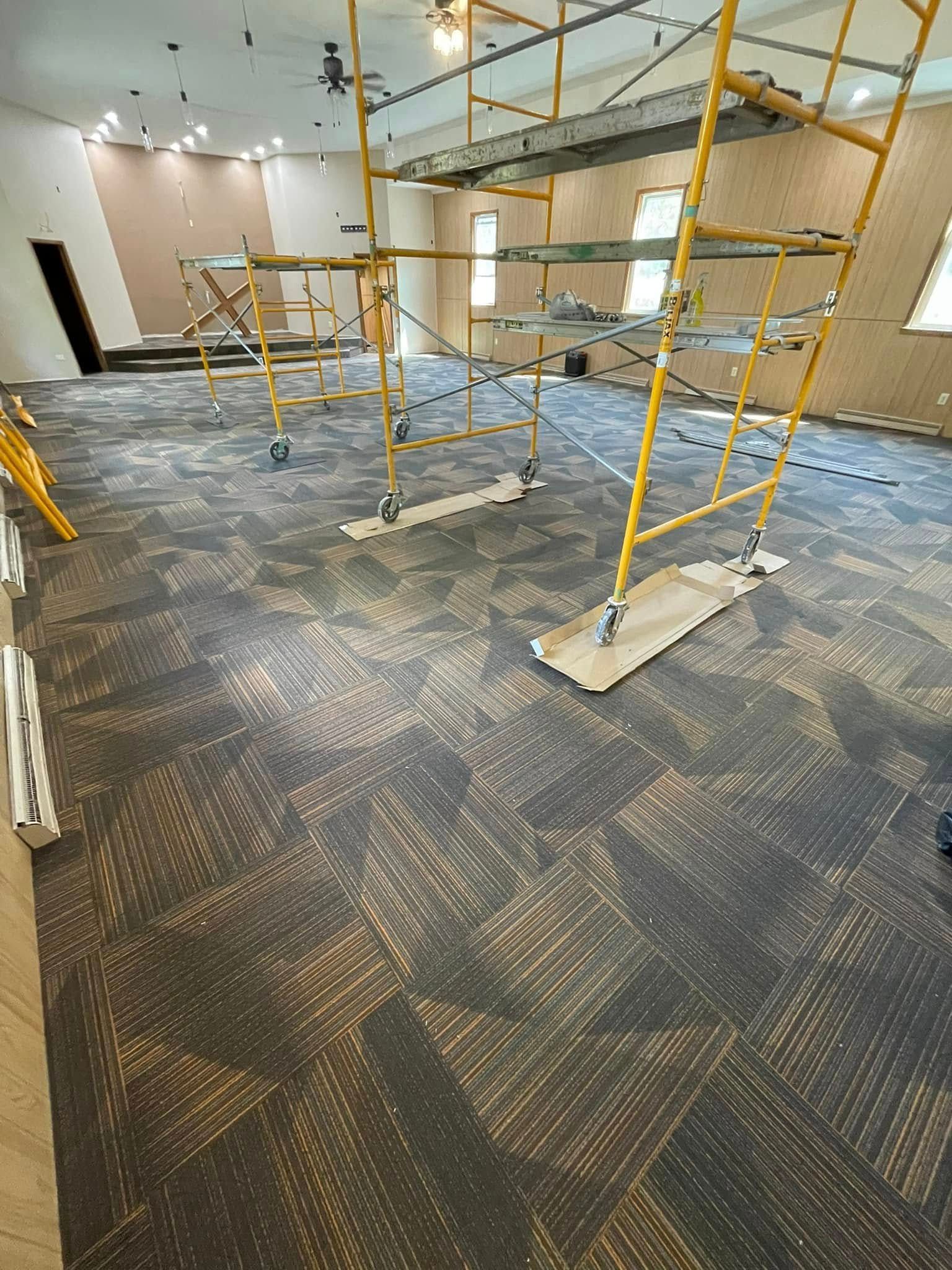 Room under renovation, showing new carpet, scaffolding, and light fixtures.