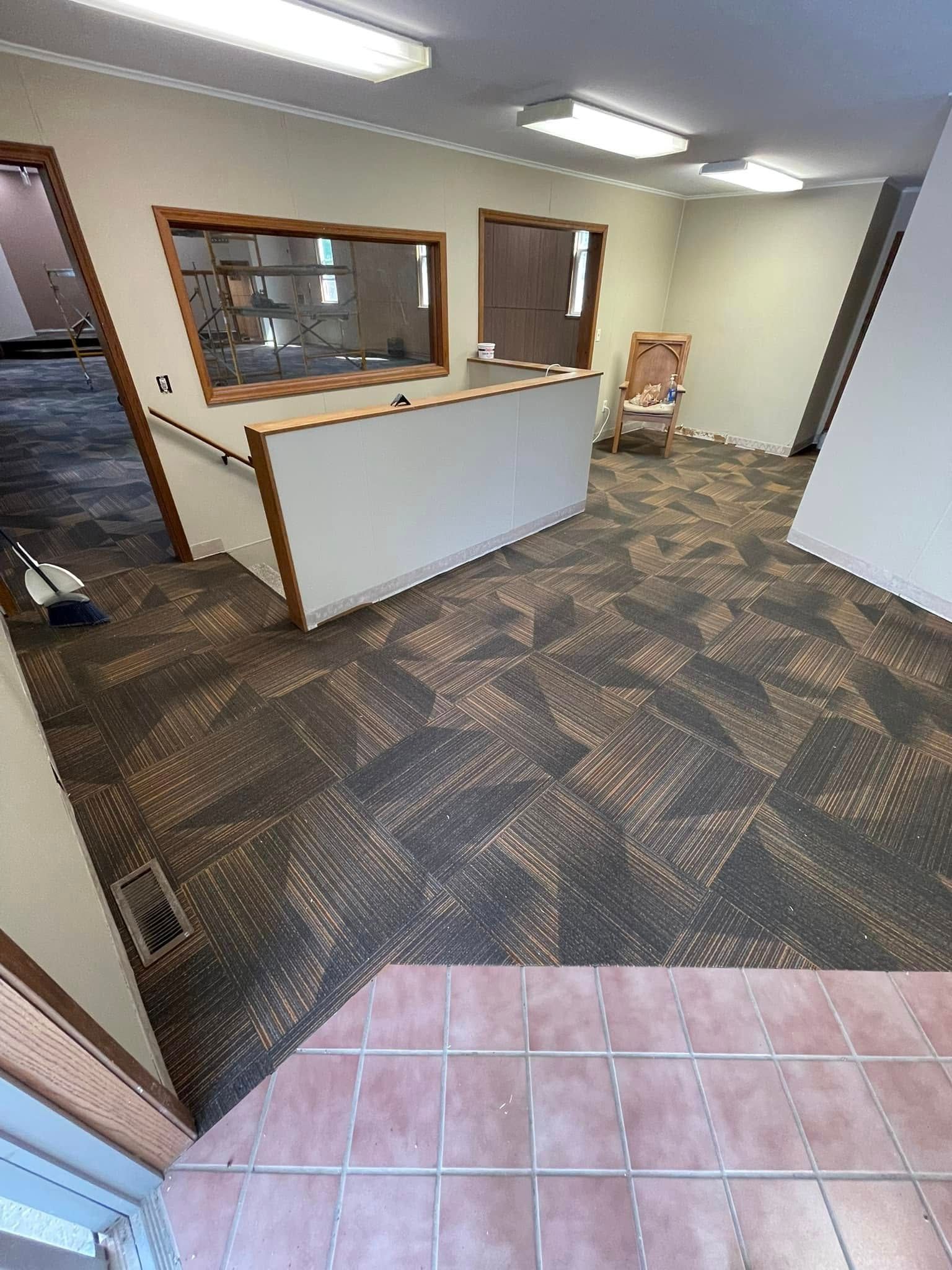An empty office with brown and tan patterned carpet, white walls, and a reception desk.