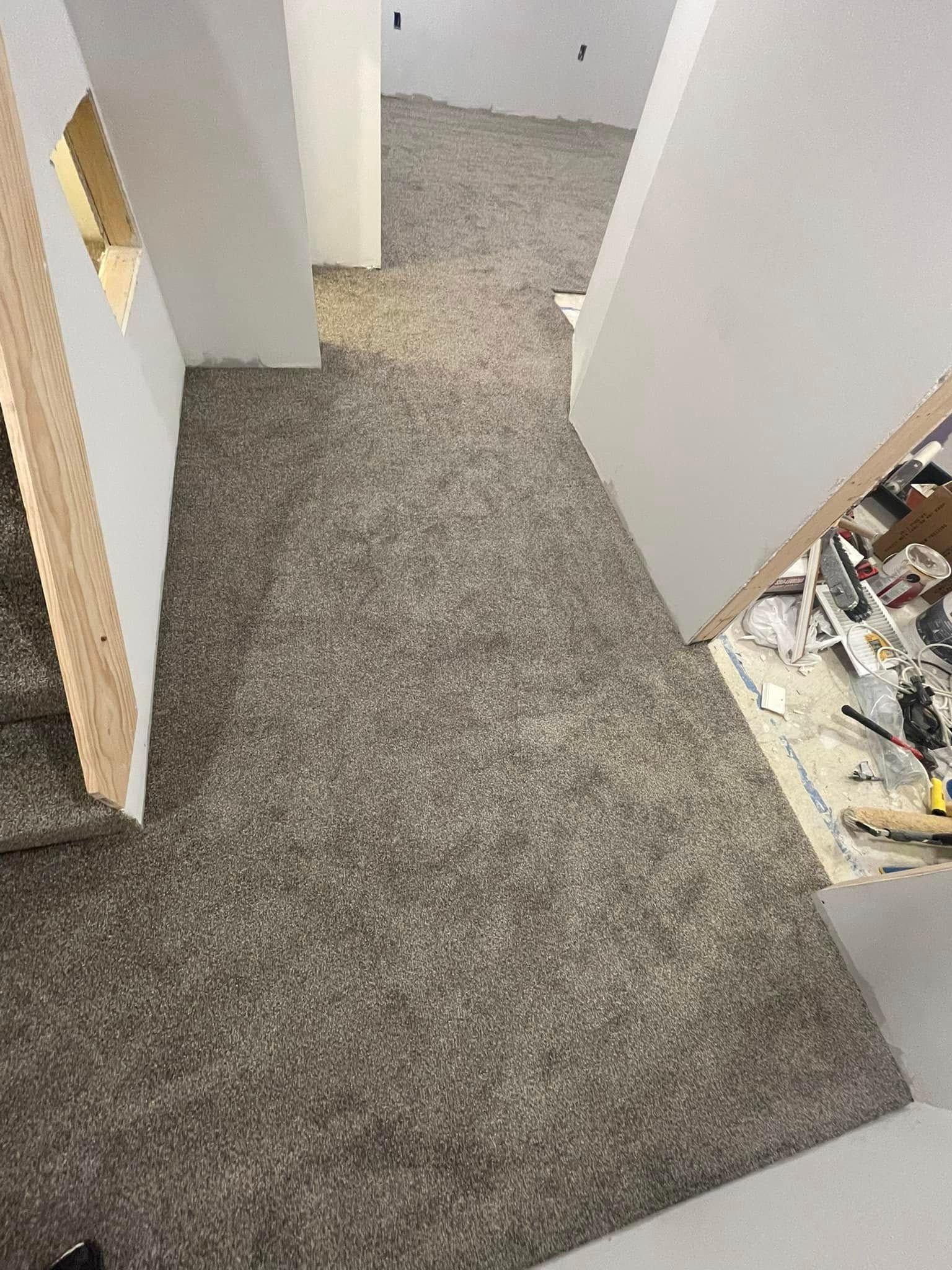 Hallway with new brown carpet. Stairs on left, doorway on right, white walls.