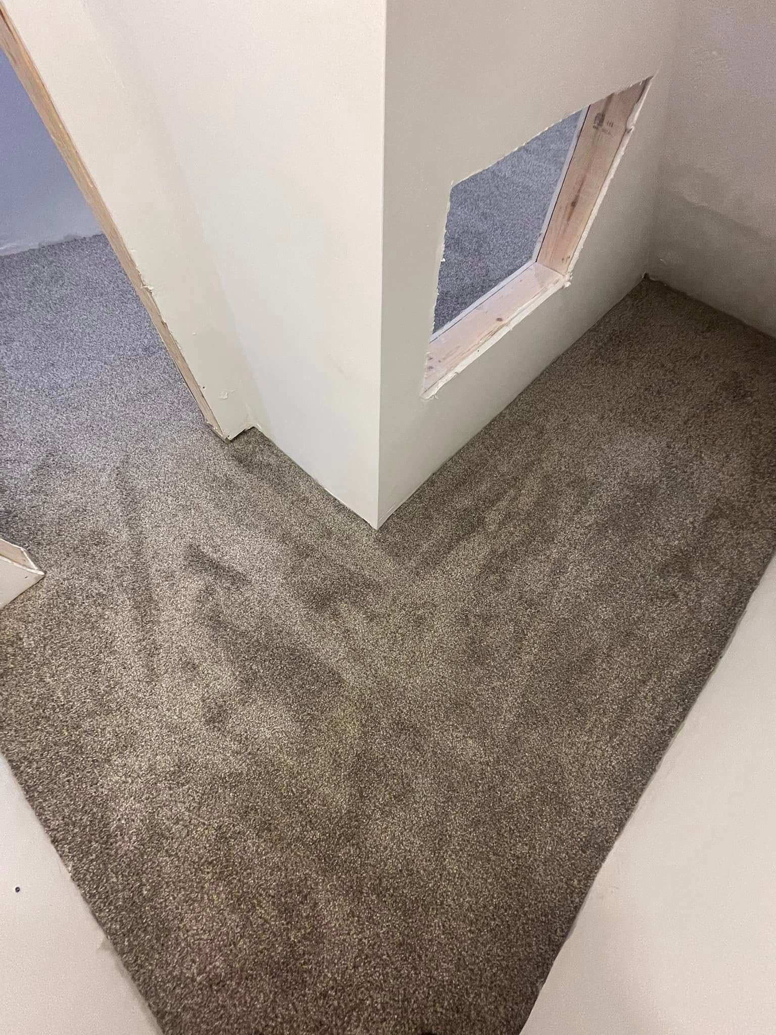 Corner of a room with gray carpet and a white wall with a square cutout.