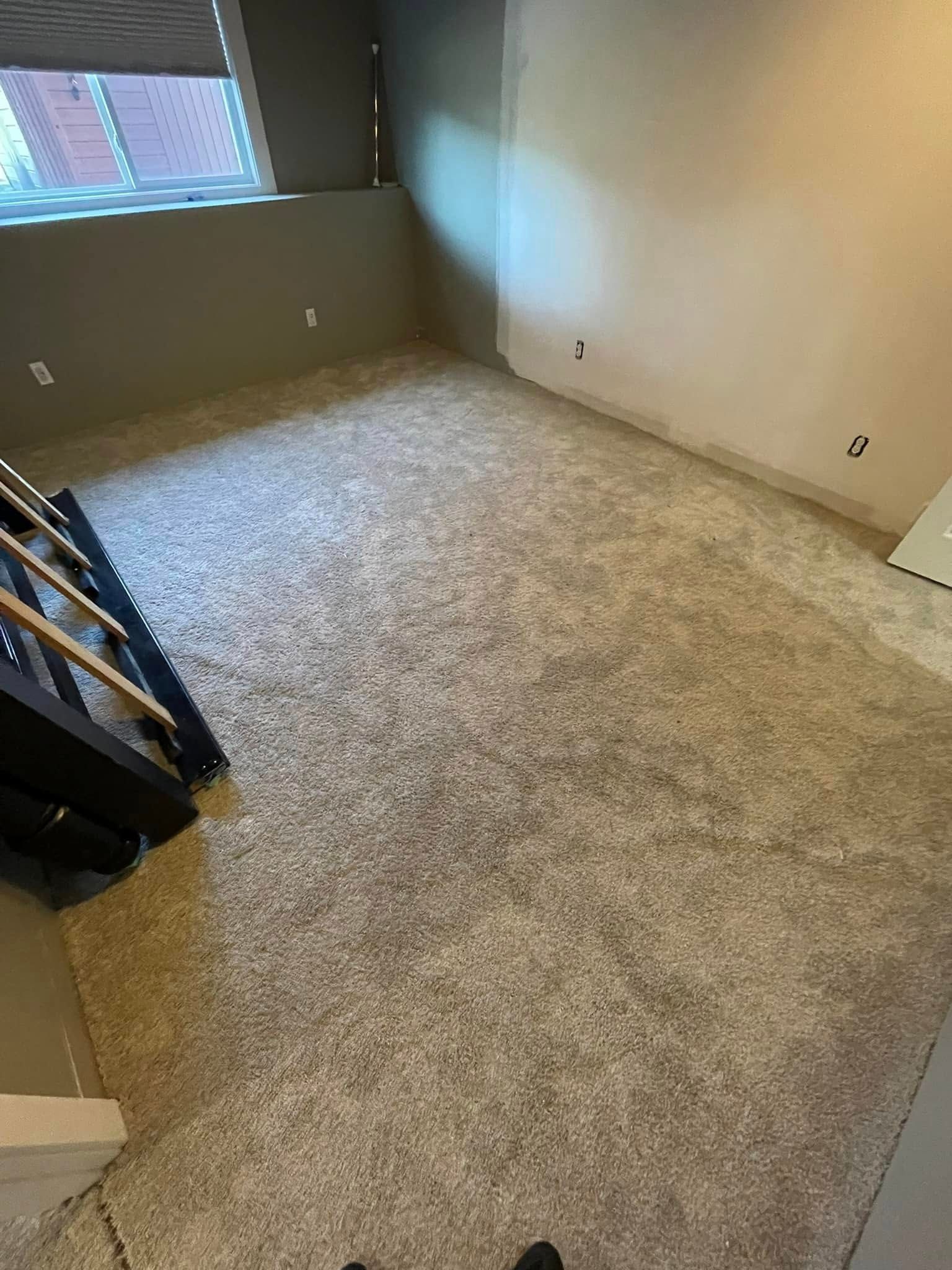 Empty room with new grey carpet and stairs to the left.