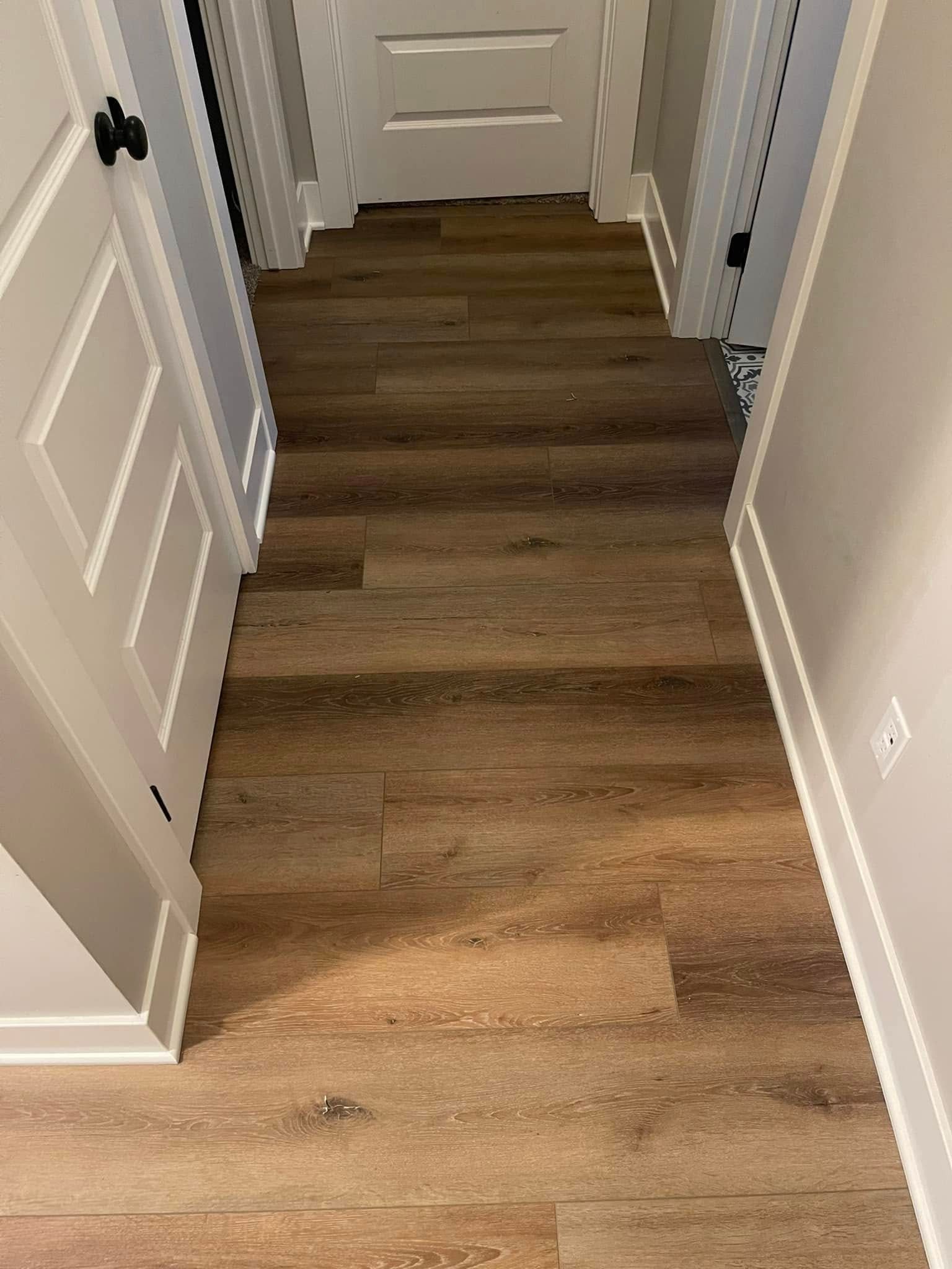 Hallway with wood-look flooring, white doors, and trim.