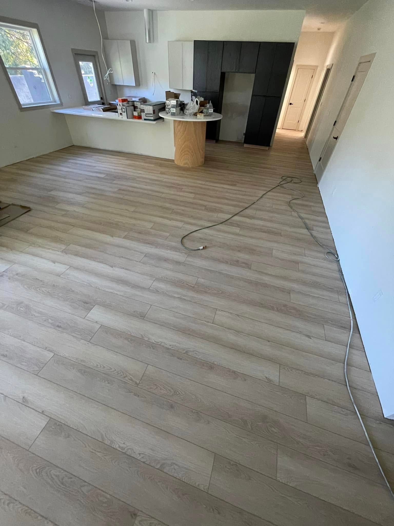 Light wood-look flooring installed diagonally in a mostly empty room with a kitchen island.
