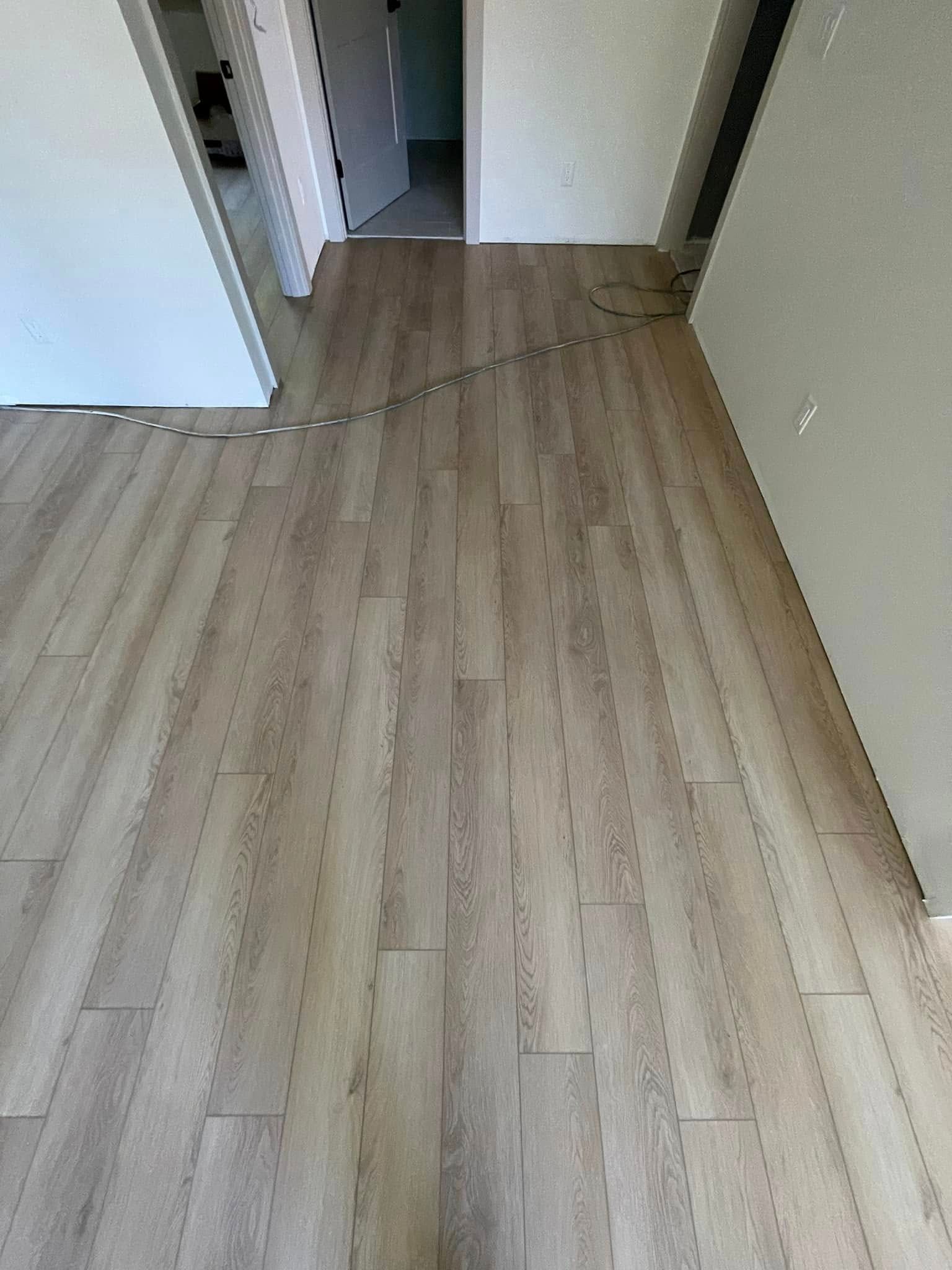 Wooden floor in a hallway with open doors, overhead view.