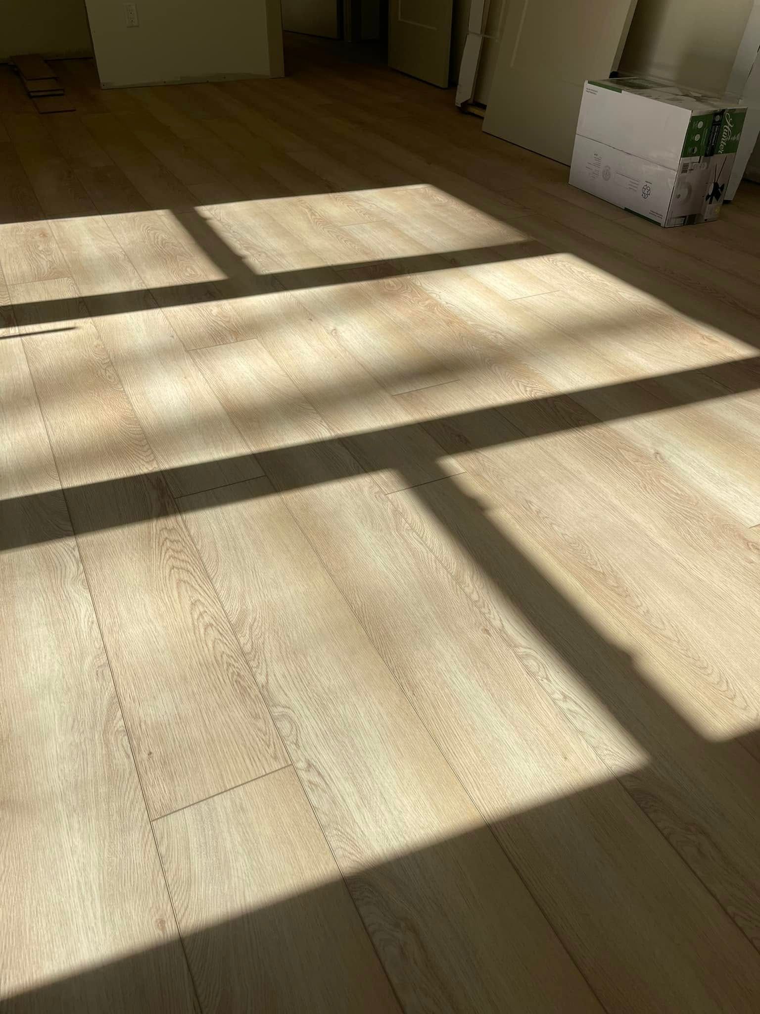 Sunlight casts shadows on a wood-look floor in a room.