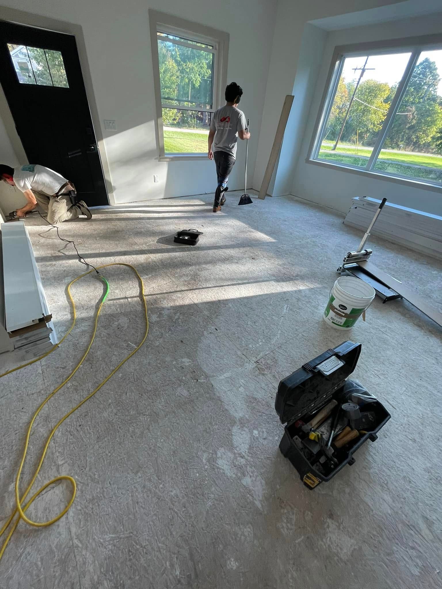 Person inside room with tools, working on what appears to be a construction project. Room has windows.
