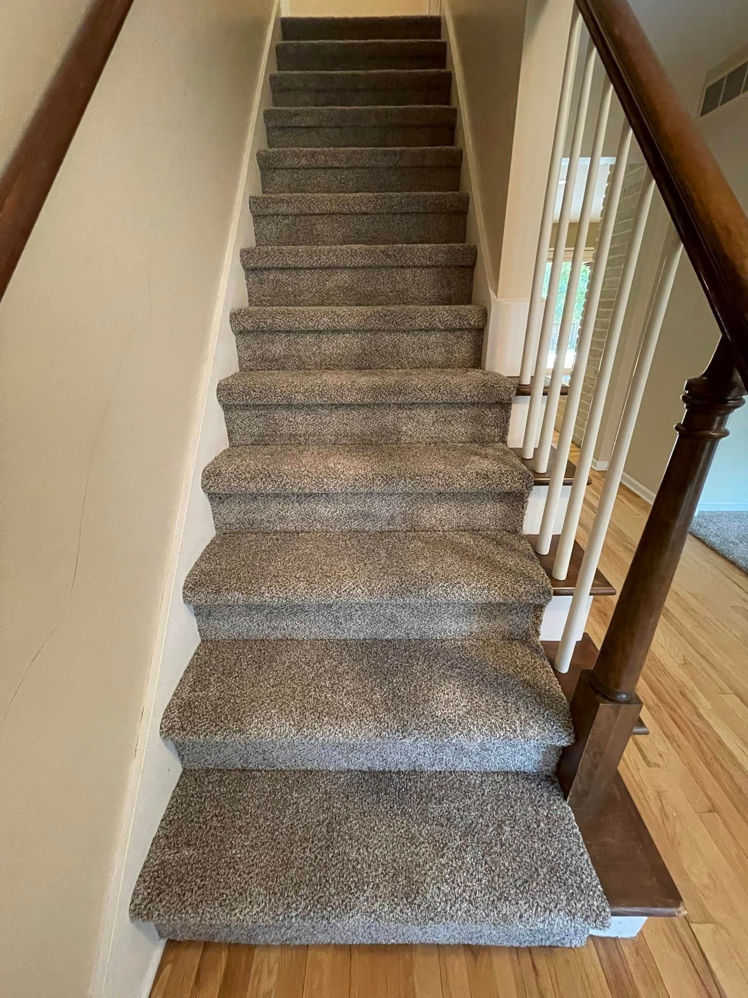 Carpeted staircase with wooden handrails and spindles, leading upwards.