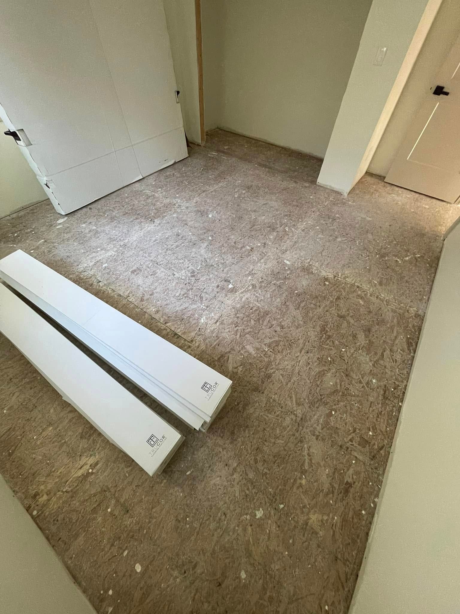 Room with unfinished floor, white trim, and door frame.