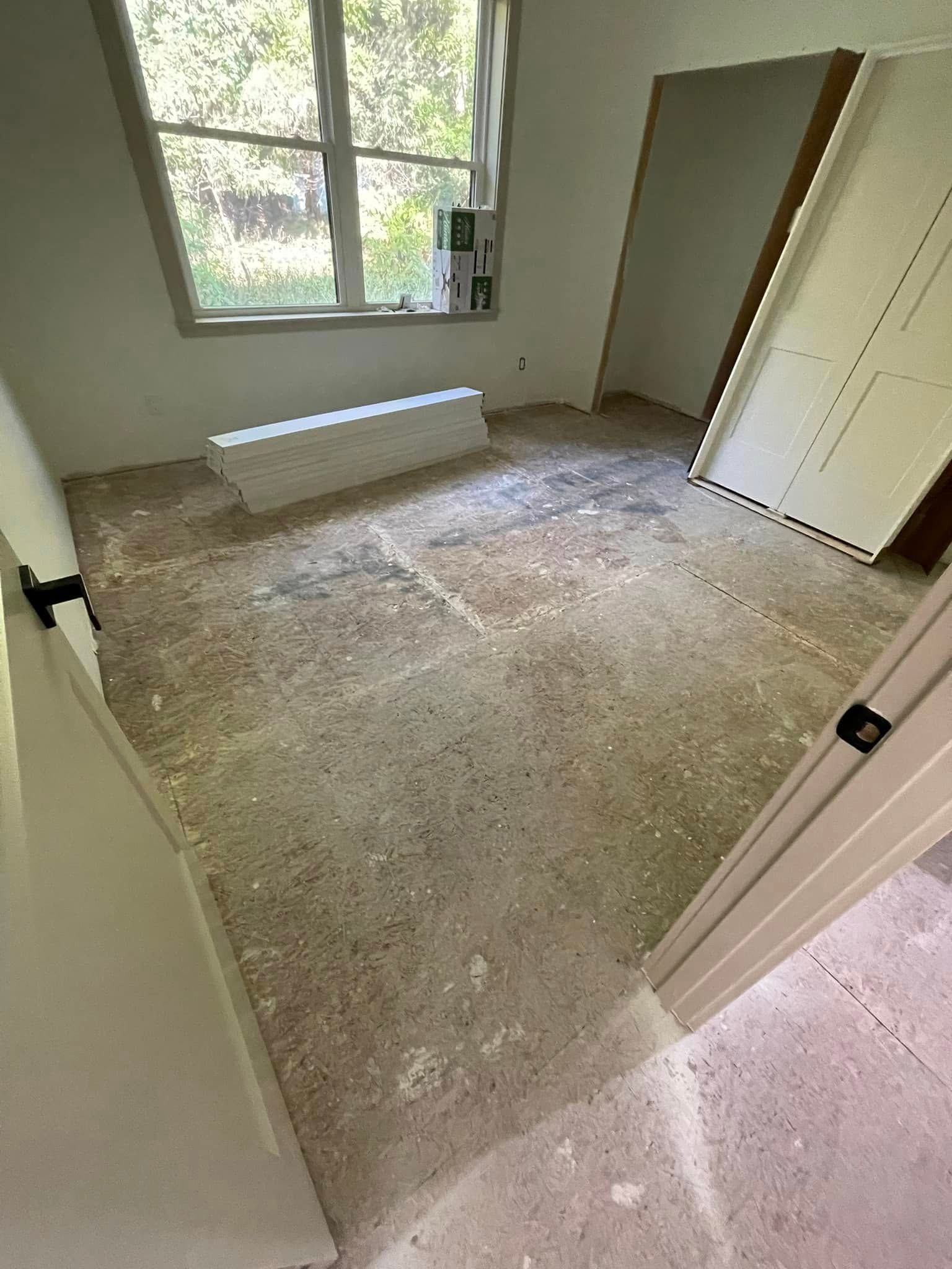 Empty room with unfinished concrete floor, window, and doors.