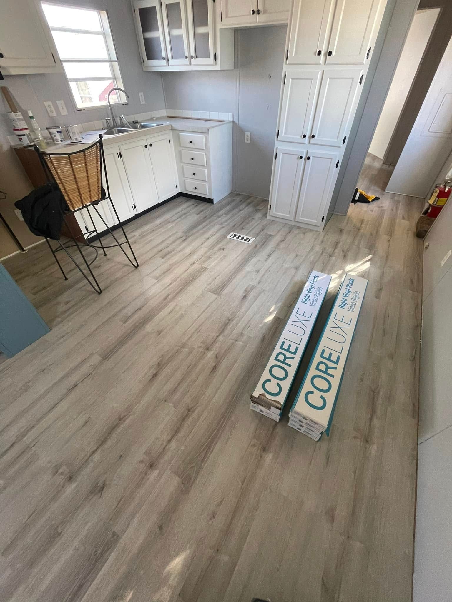 Interior view of a kitchen with light wood-look flooring and two boxes of COREtec flooring.