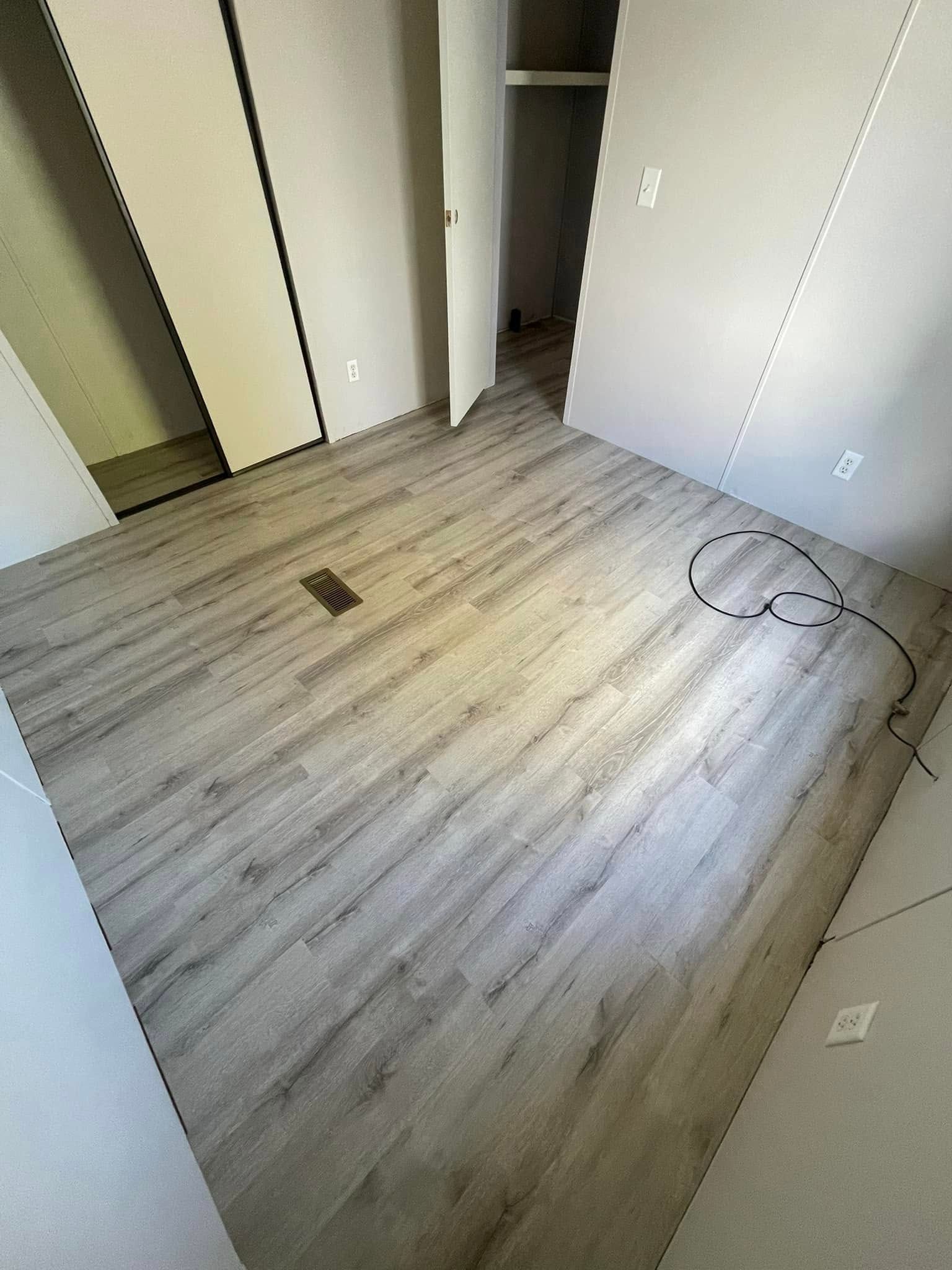 Empty room with light wood-look flooring. White walls and door to a closet. A cable runs across the floor.
