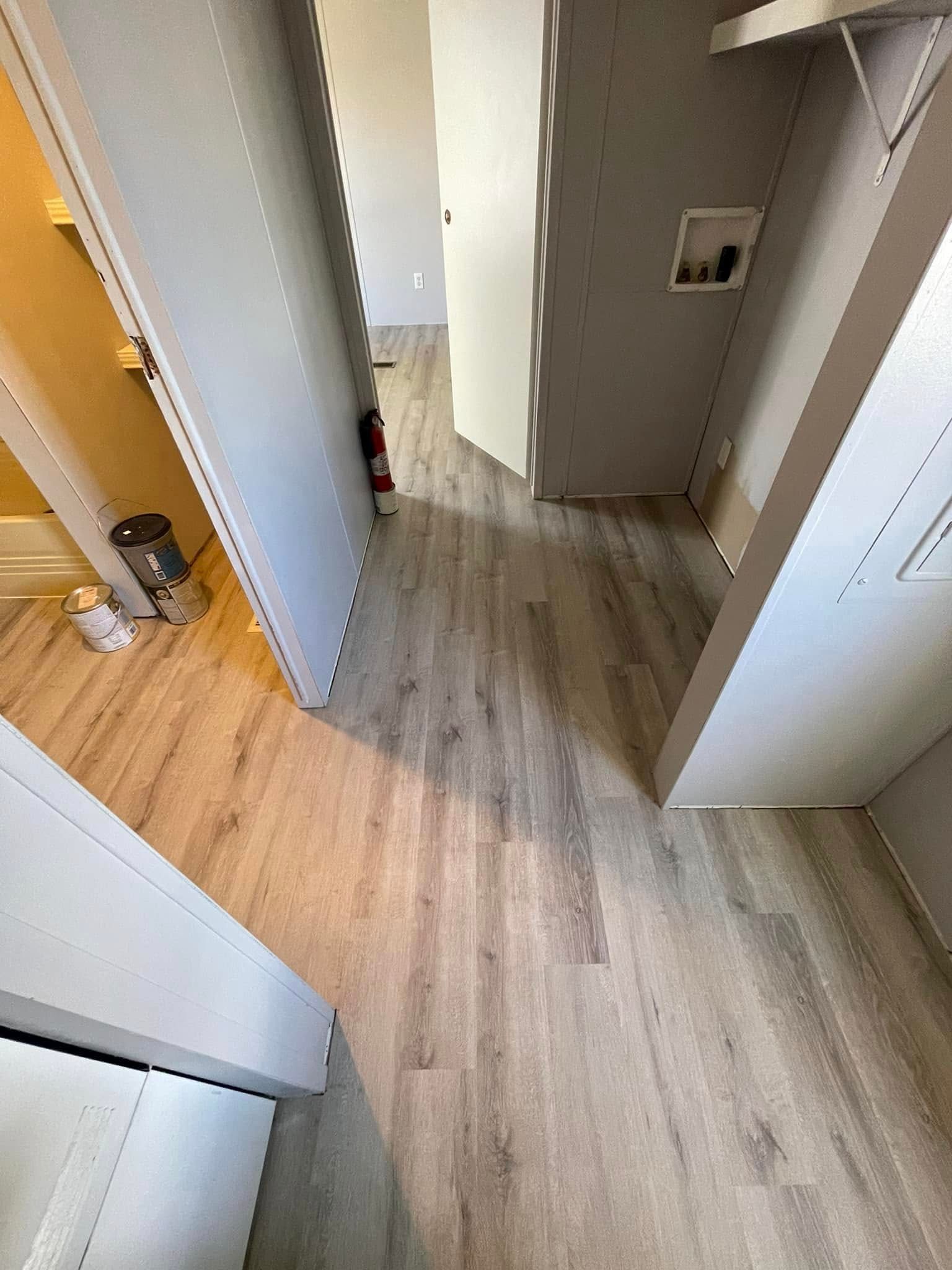 Hallway with light wood-look flooring, doors, and a laundry area. A fire extinguisher is visible.