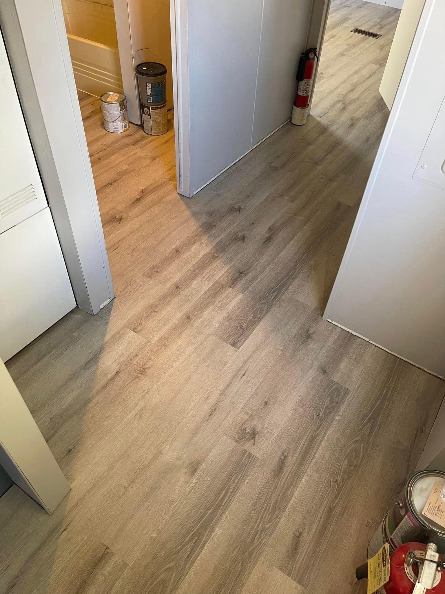 Hallway with light wood-look flooring, white doors, and a fire extinguisher.