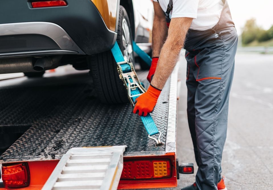 A man is tying a car to a tow truck.