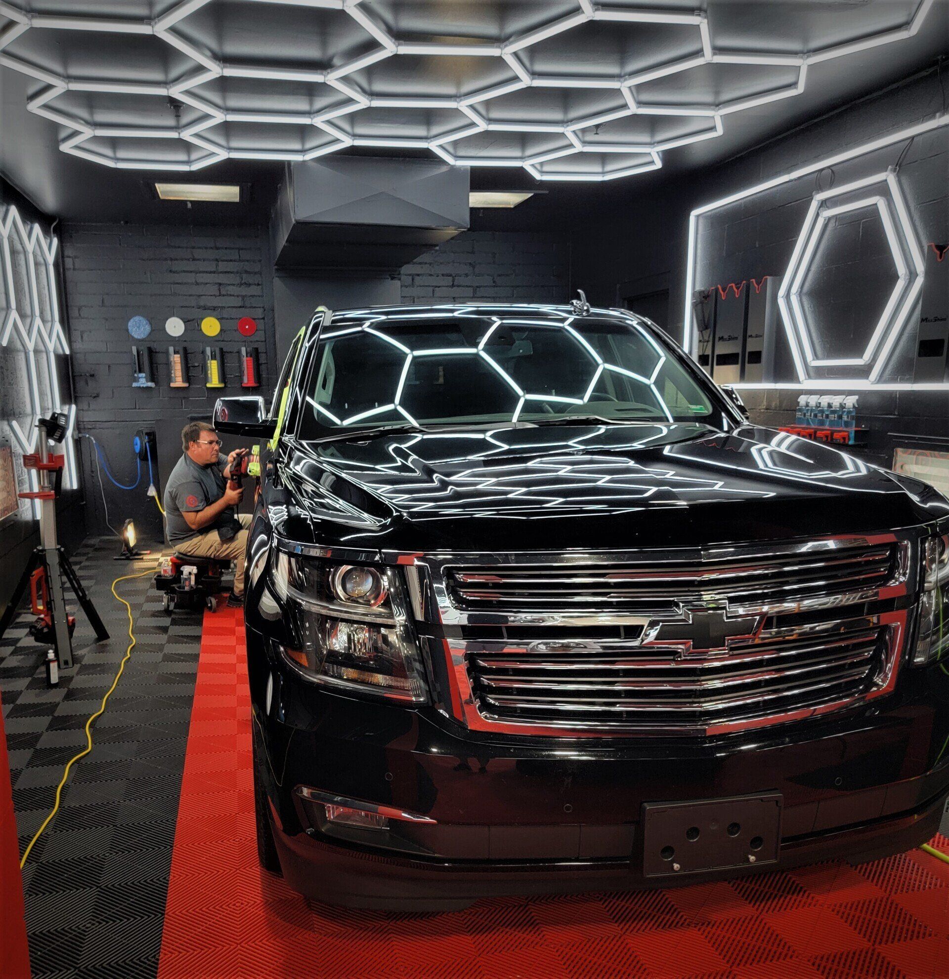 A black suv is parked in a garage with lights on the ceiling