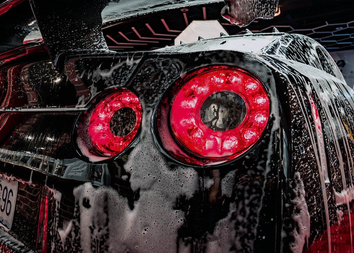 A close up of a car being washed with soap and water.