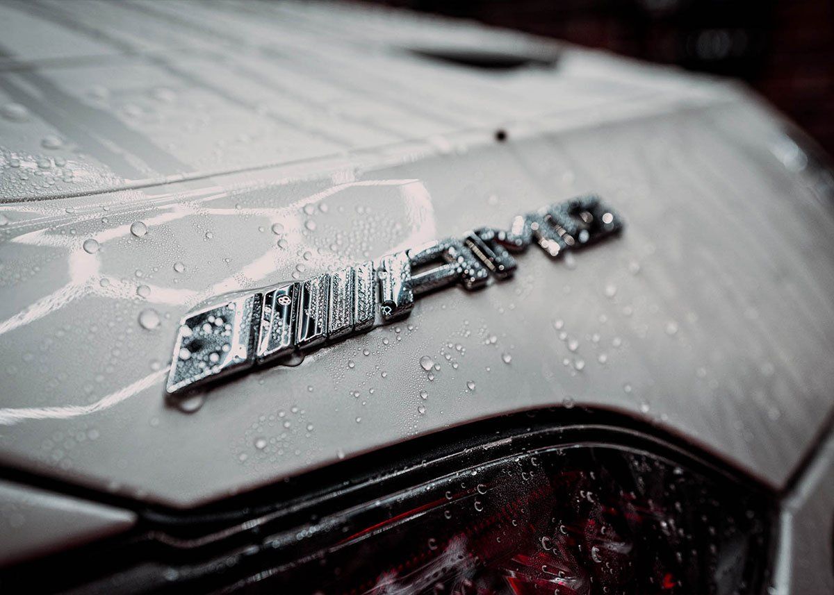 A close up of the hood of a car with water drops on it.