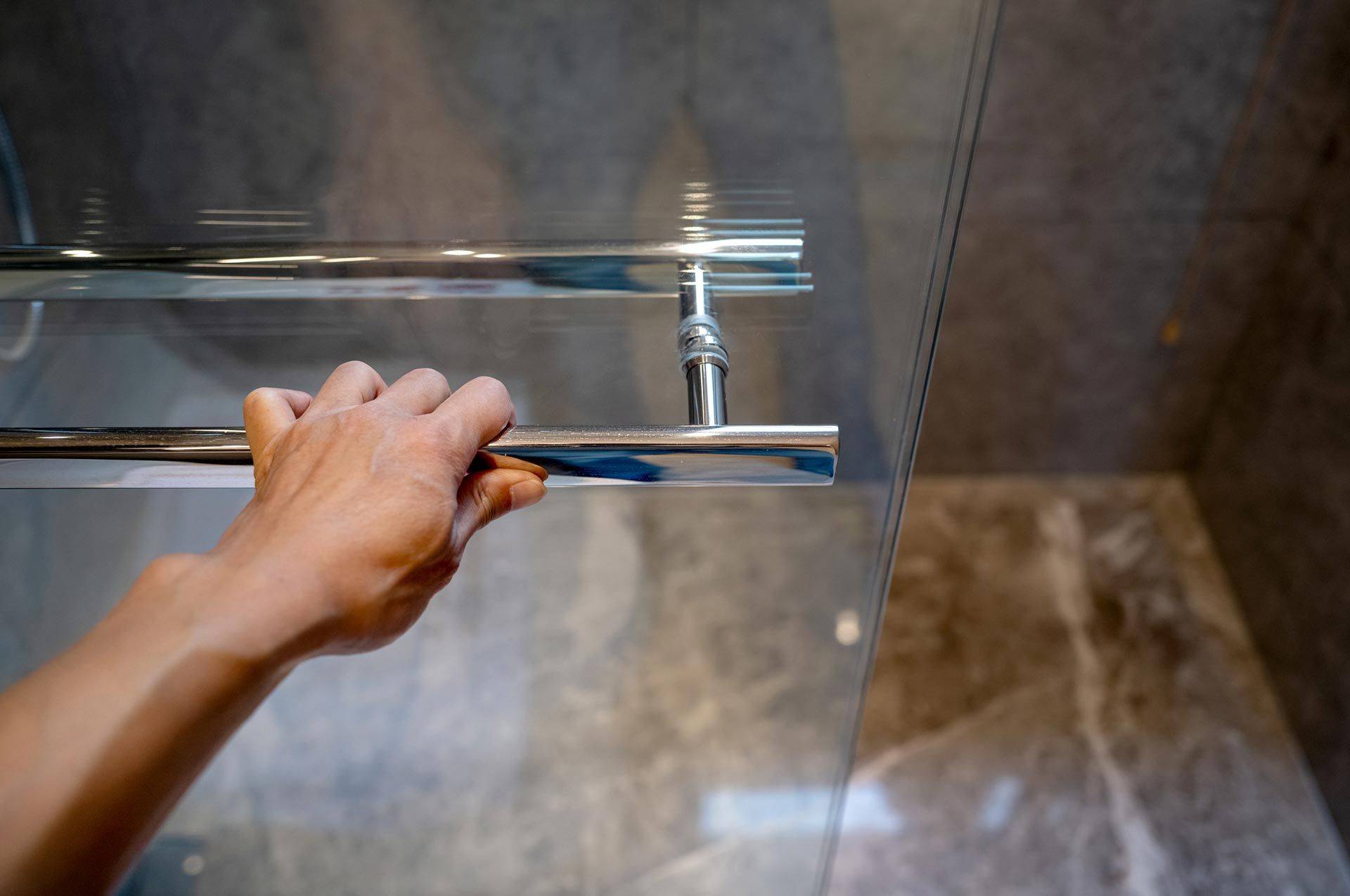 Hand pulling a bathroom sliding glass door.