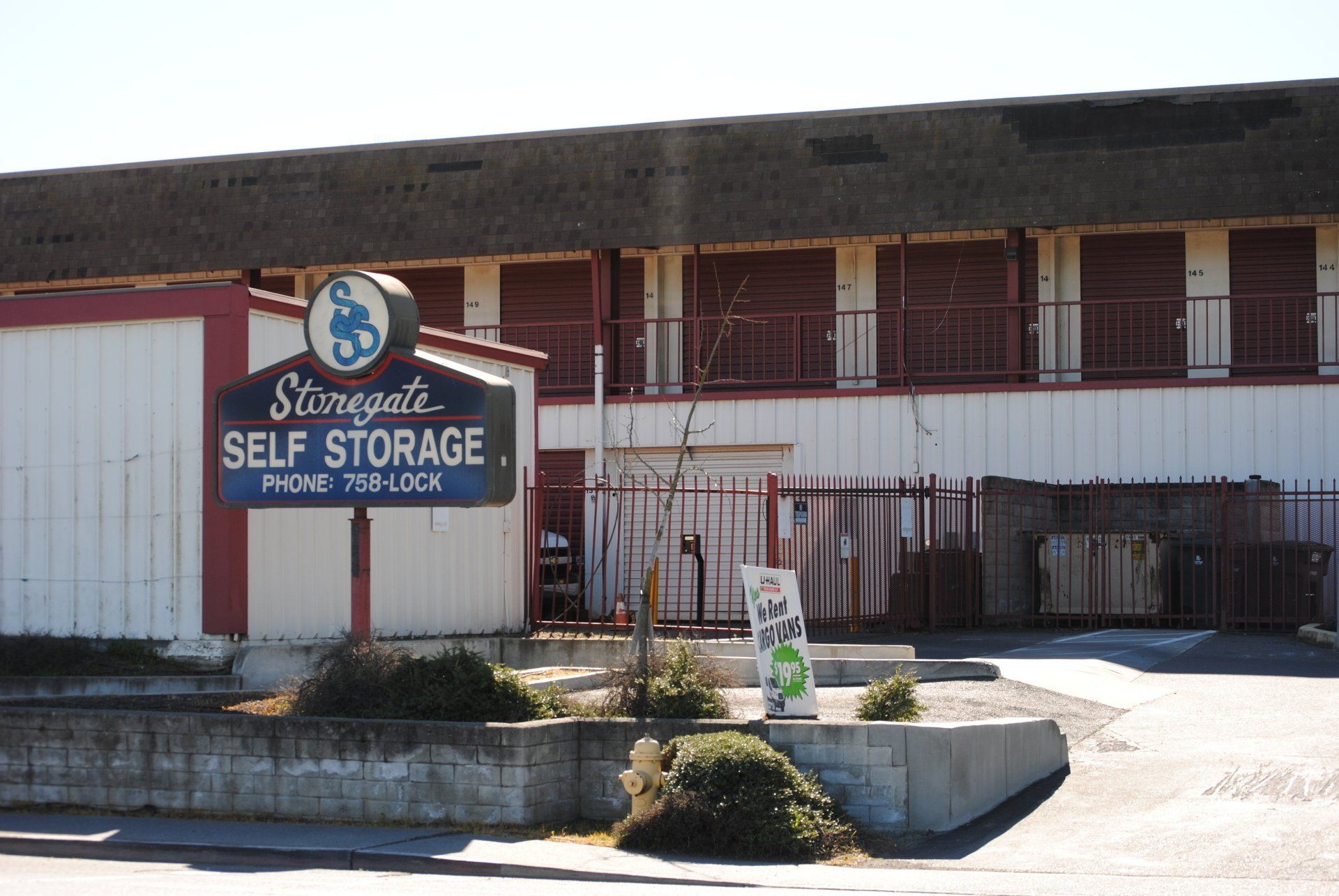 Stonegate Self Storage sign with storage units behind gate.