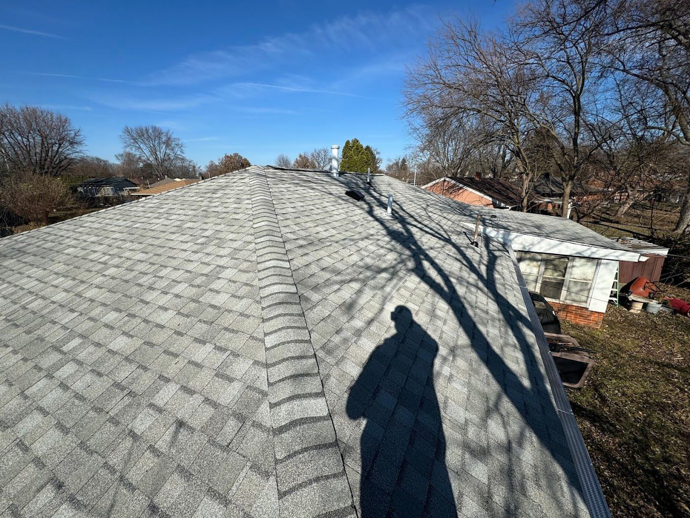 A shadow of a person is cast on the roof of a house.