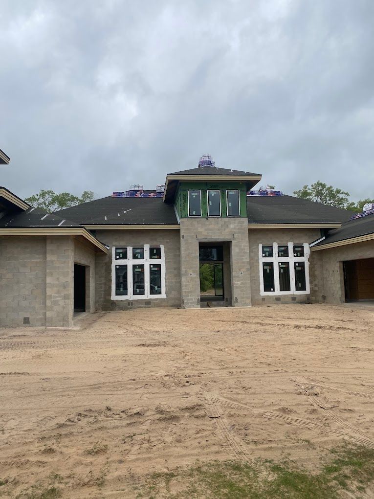 A large house is being built in the middle of a dirt field.